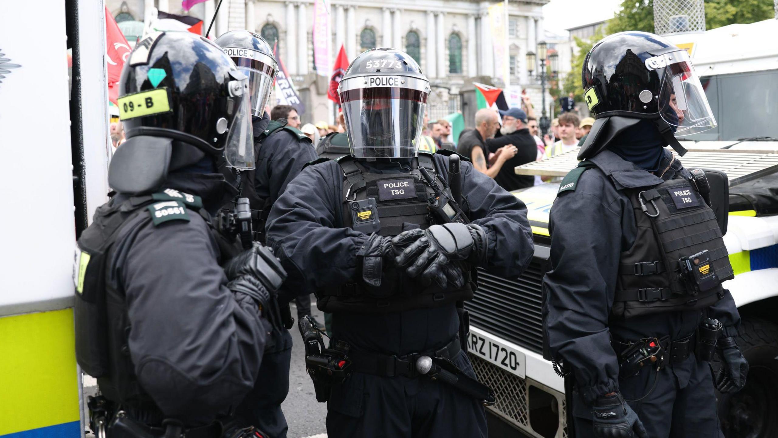 PSNI Officers in riot gear stand in front of Belfast city hall