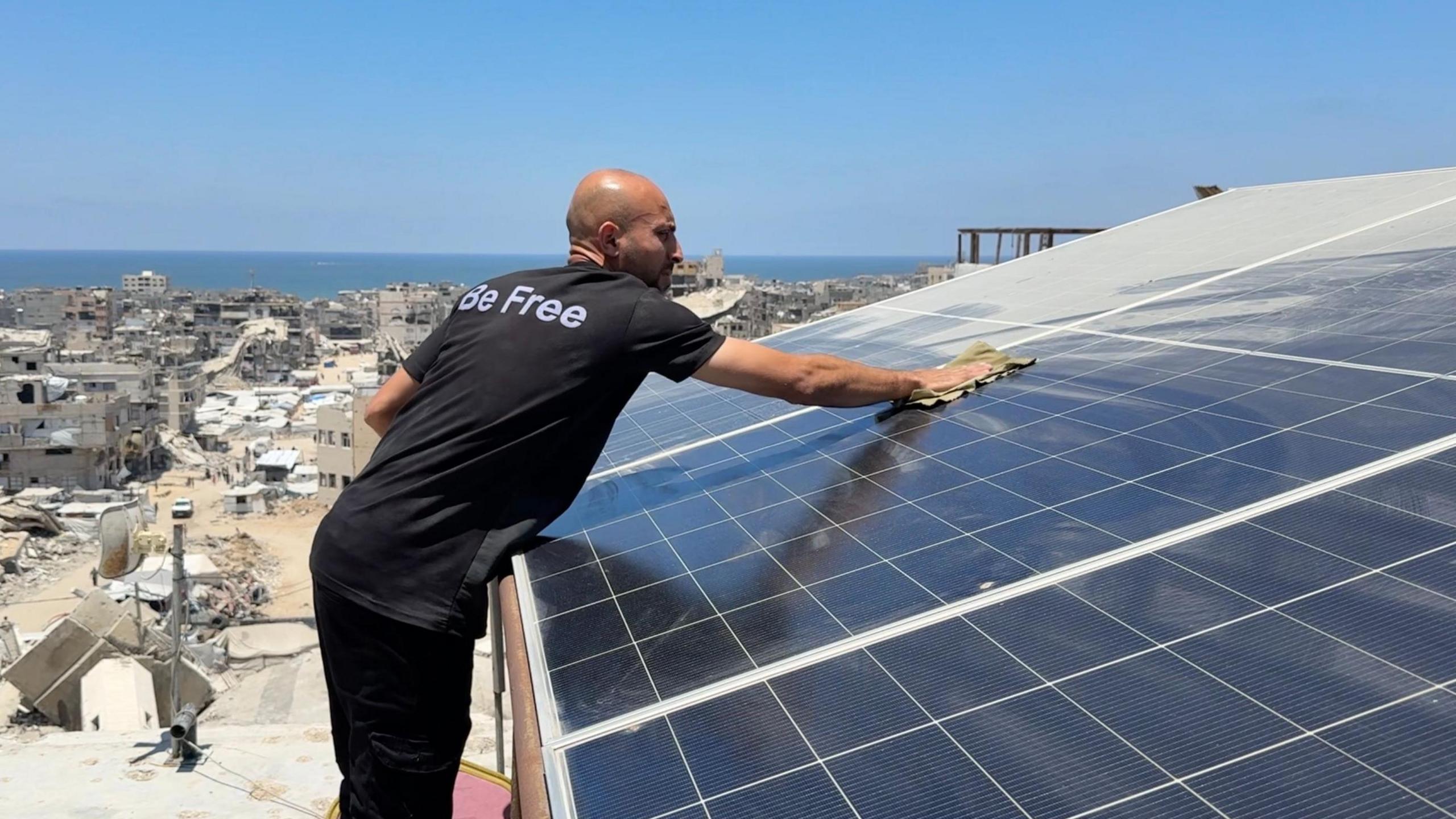 A man cleans the solar panels on top of the building where there is a co-working space for high-tech workers in Gaza City