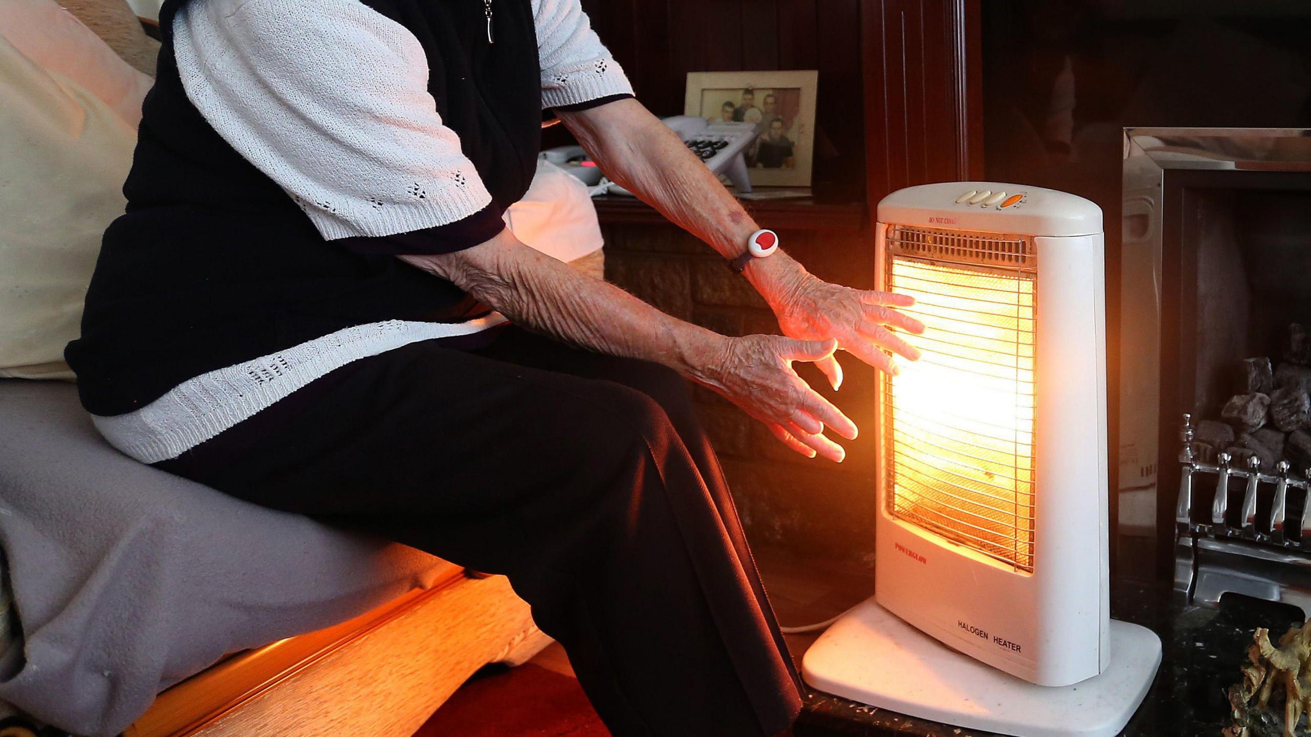 Woman warms hands on heater