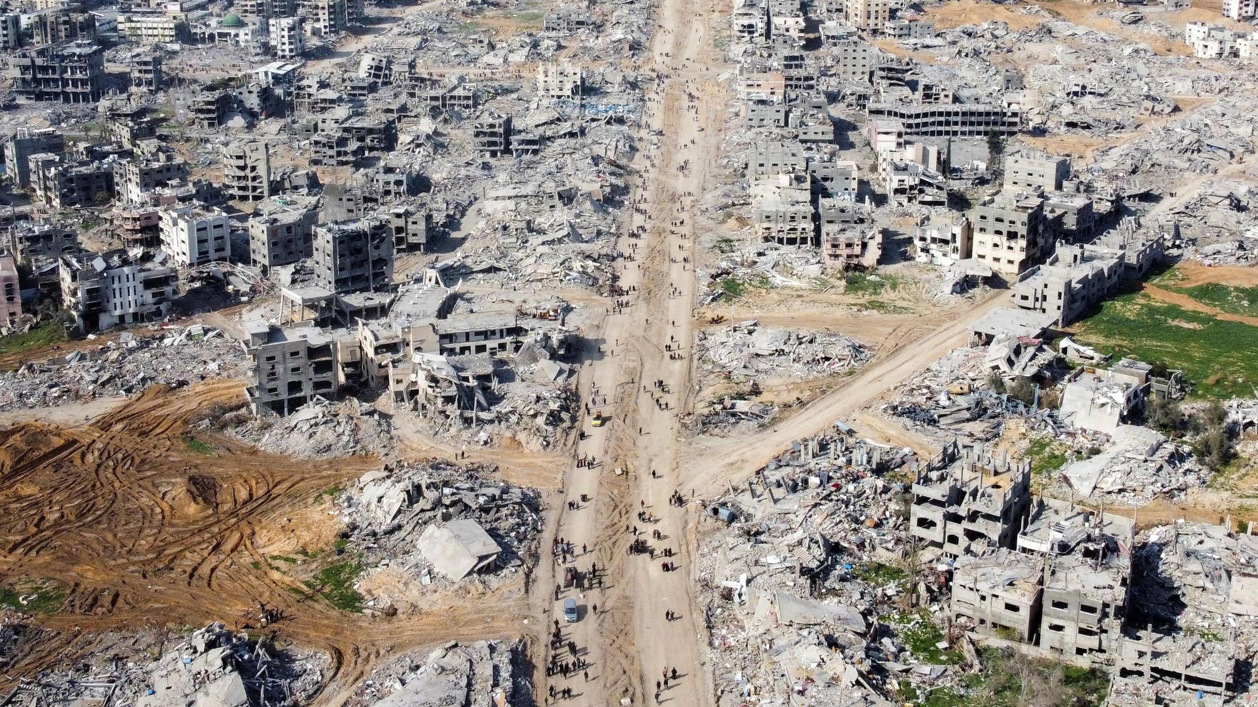 Palestinians walking past the rubble of houses and buildings, following a ceasefire between Israel and Hamas, in Jabalia in the northern Gaza Strip