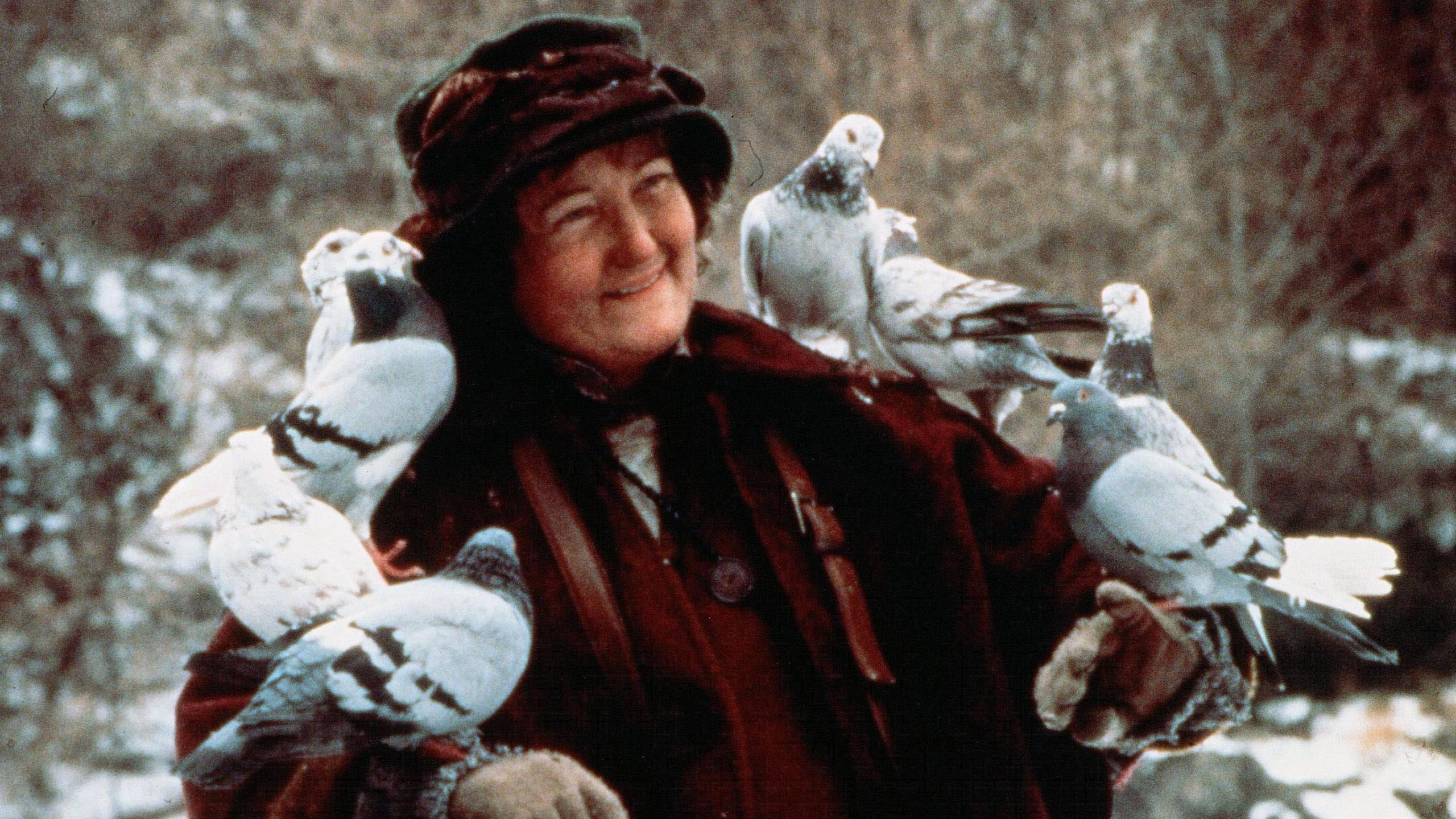Brenda Fricker with several birds perched on her arms in a scene from Home Alone 2