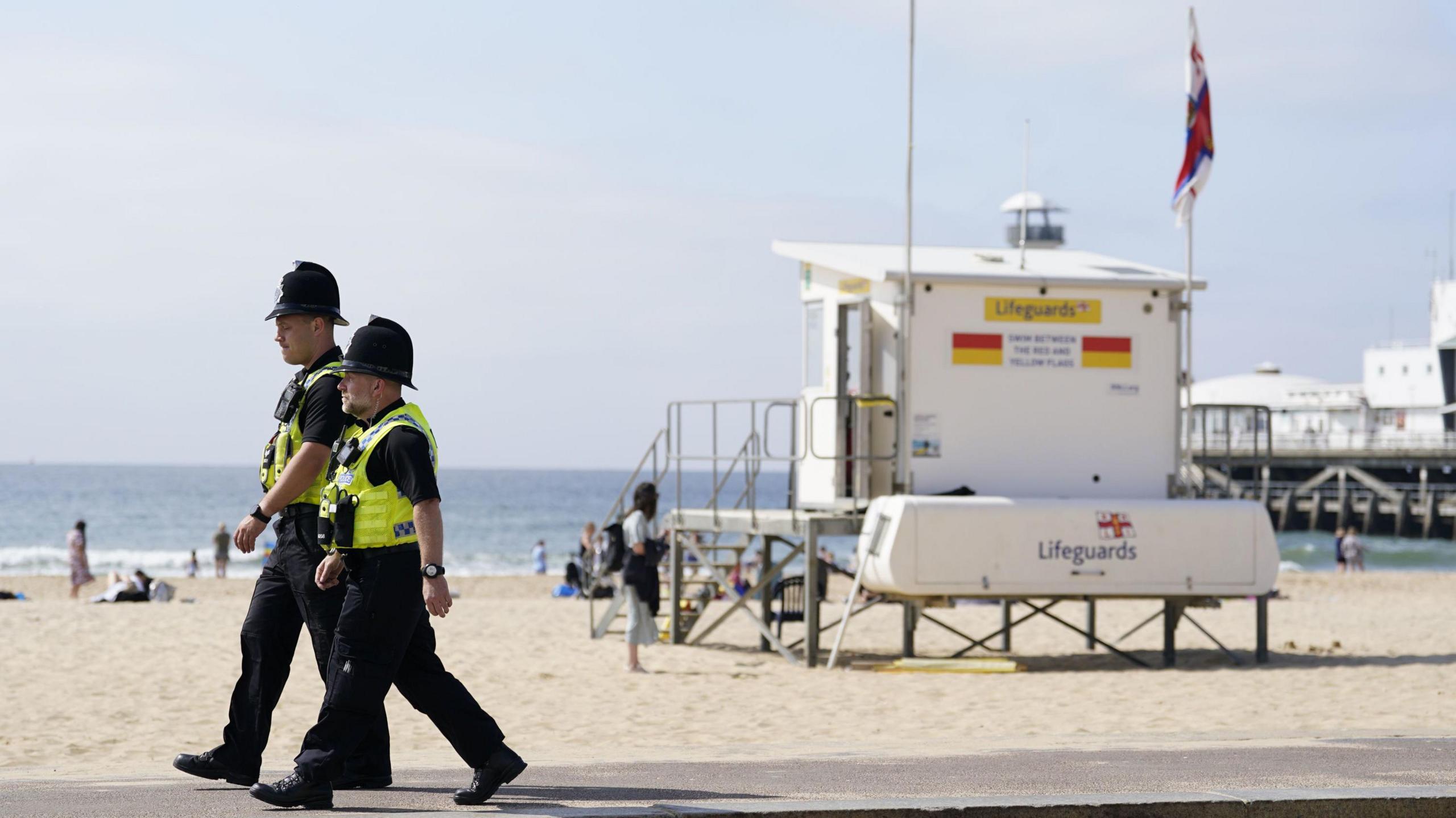 Two police officers walking along the promenade next to Bournemouth Beach