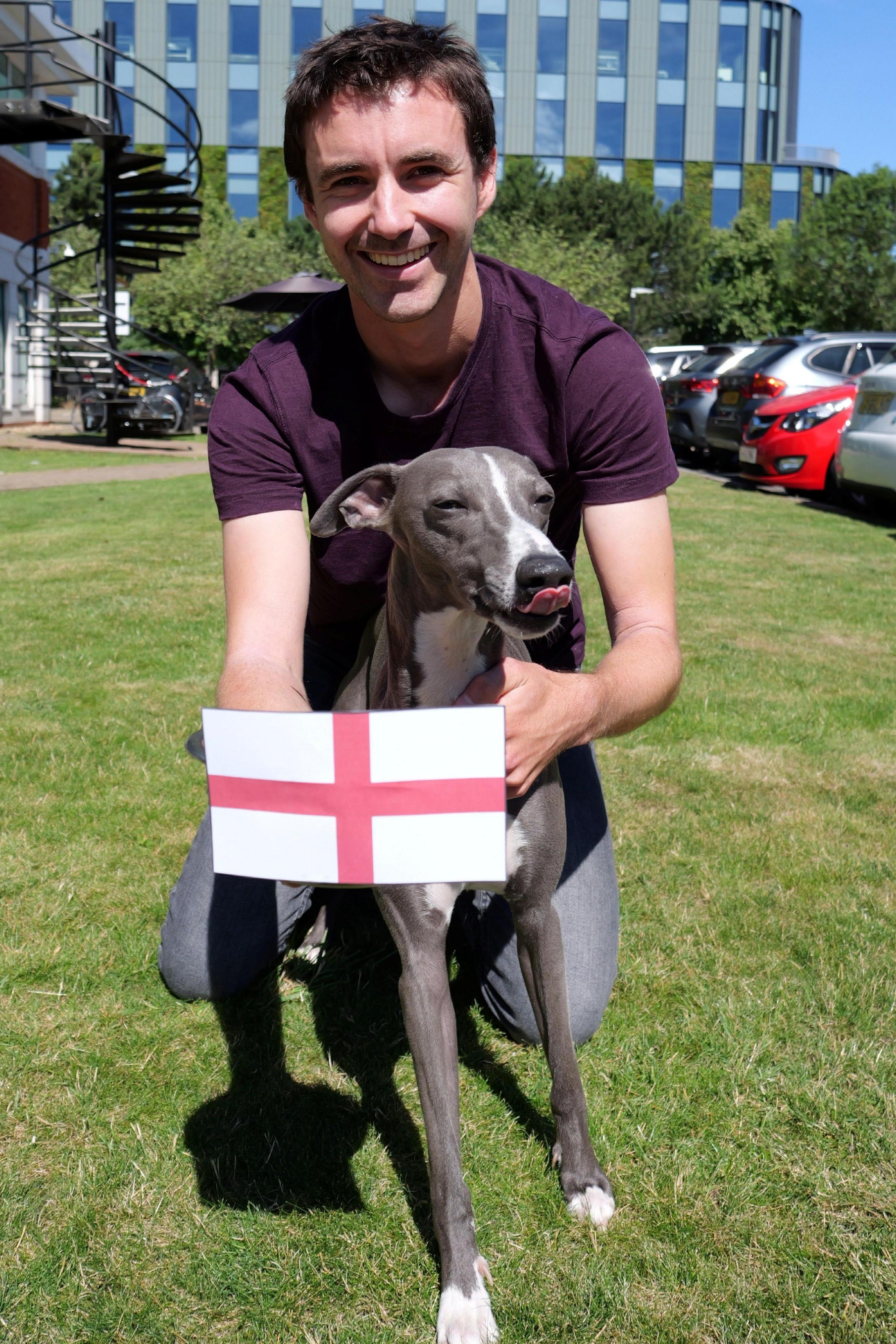 winston the dog with his owner, who is holding a small england flag