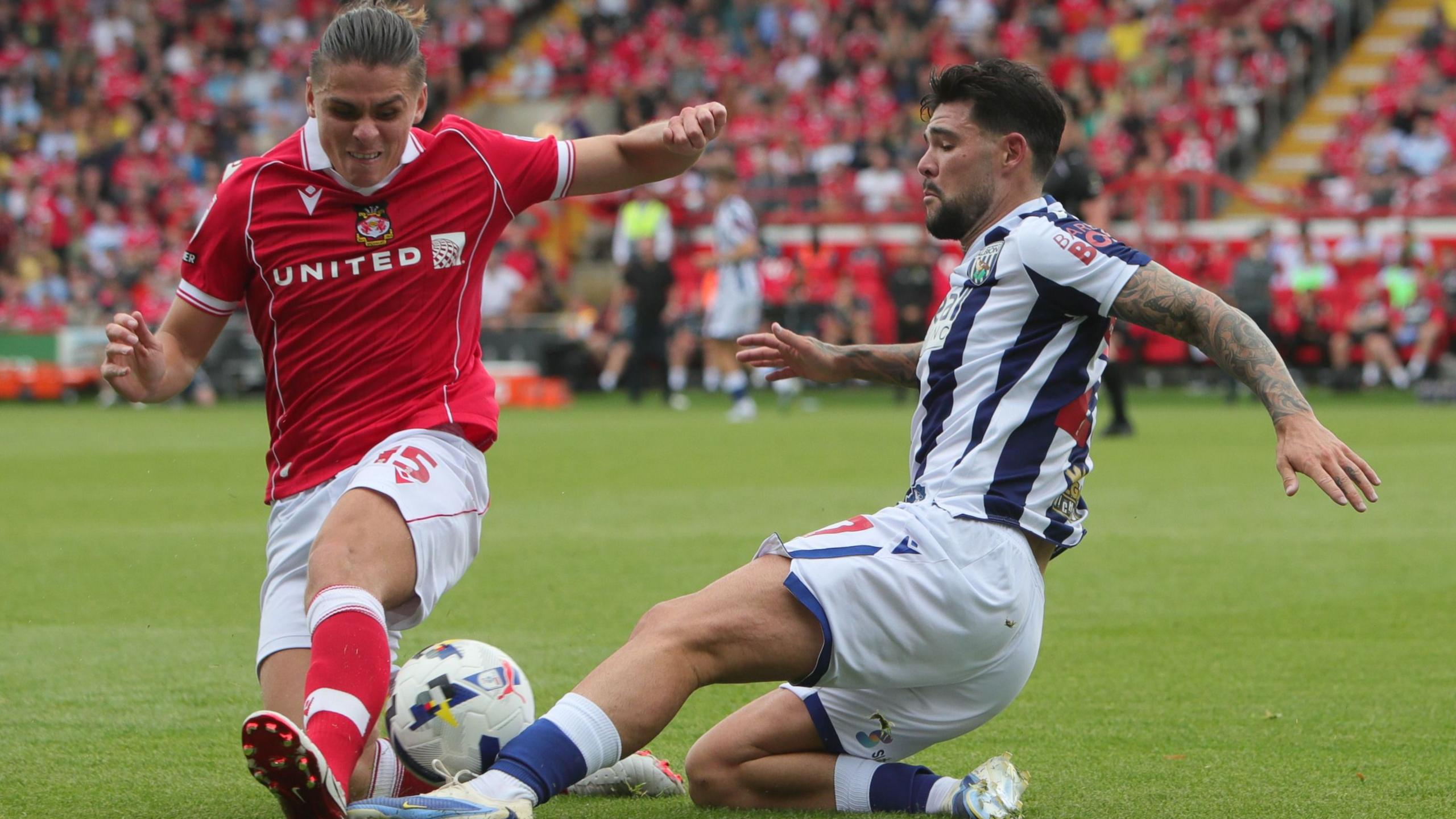Wrexham midfielder George Dobson (L) challenges West Bromwich Albion's Alex Mowatt