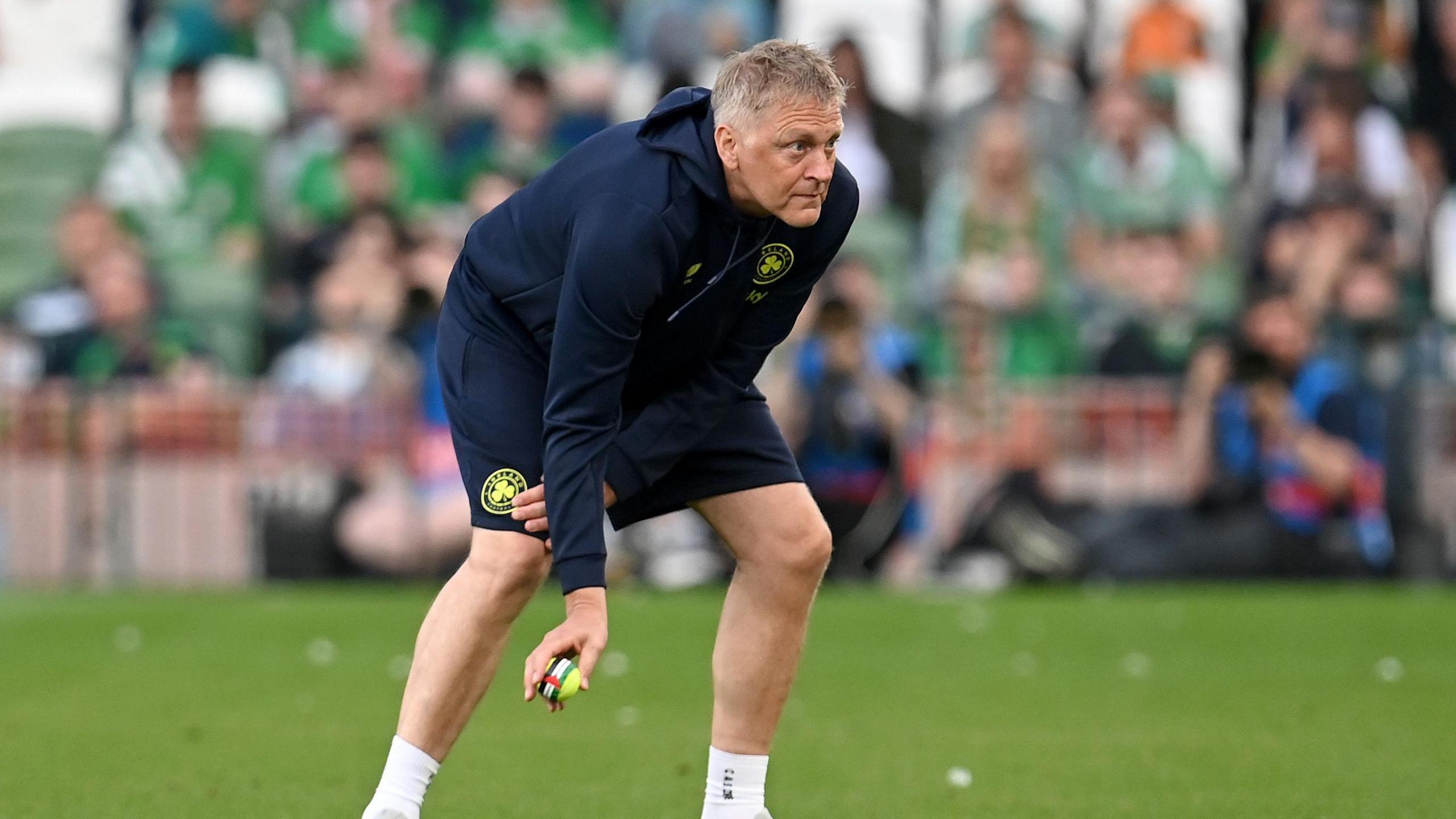 Heimir Hallgrimsson clears a tennis ball off the pitch