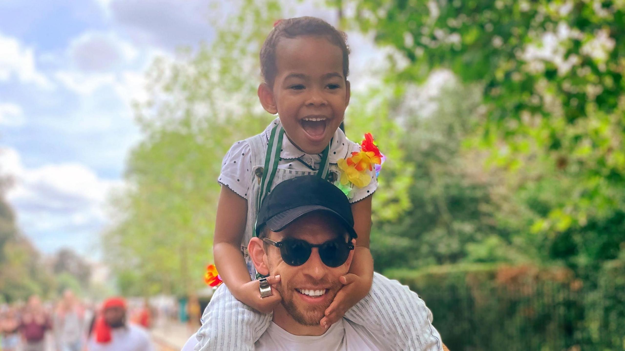 Simon smiling as he carries his daughter Isabella on his shoulders at a previous carnival