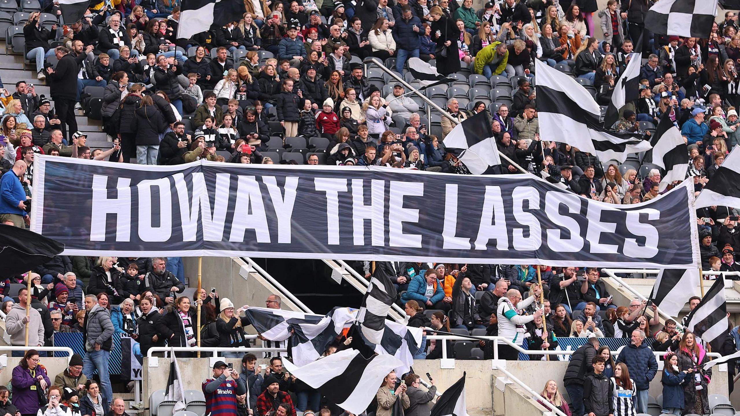 Newcastle fans hold up a banner saying Howay the Lasses at St James' Park