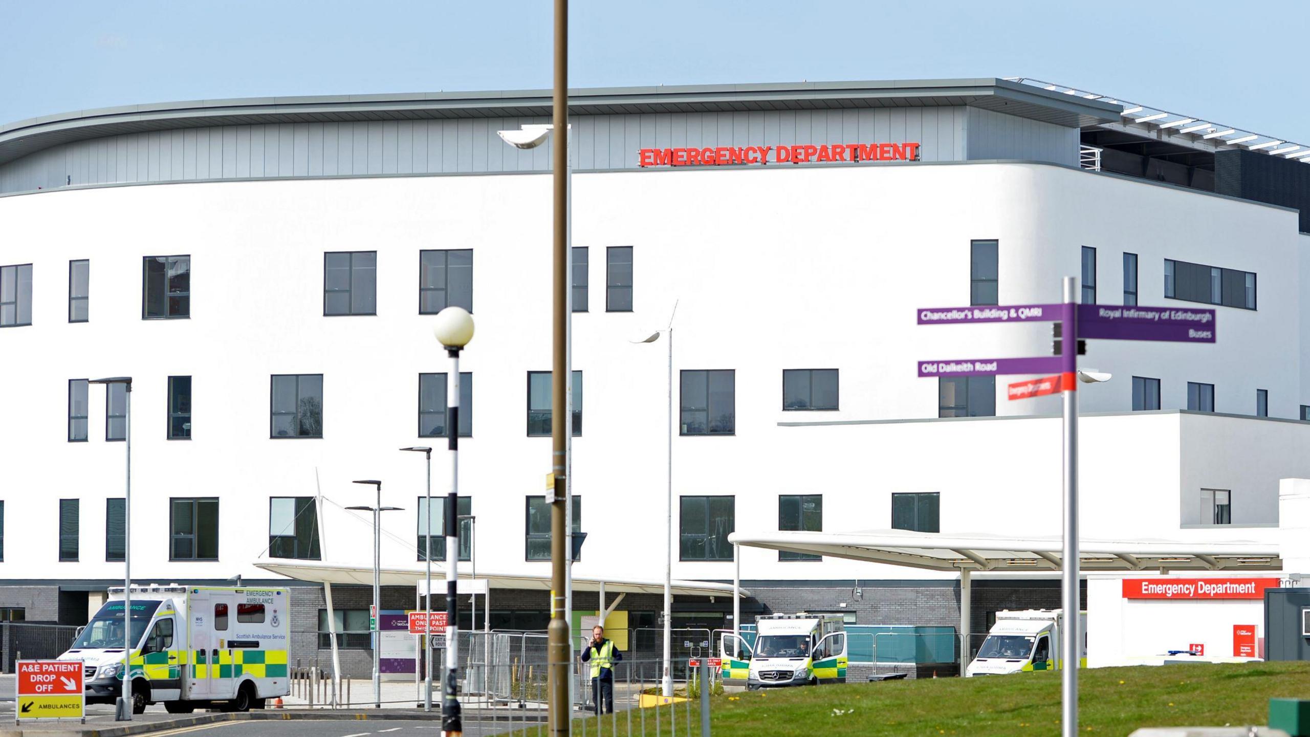 A view of the Edinburgh Royal Infirmary building, with ambulances outside and staff walking around.