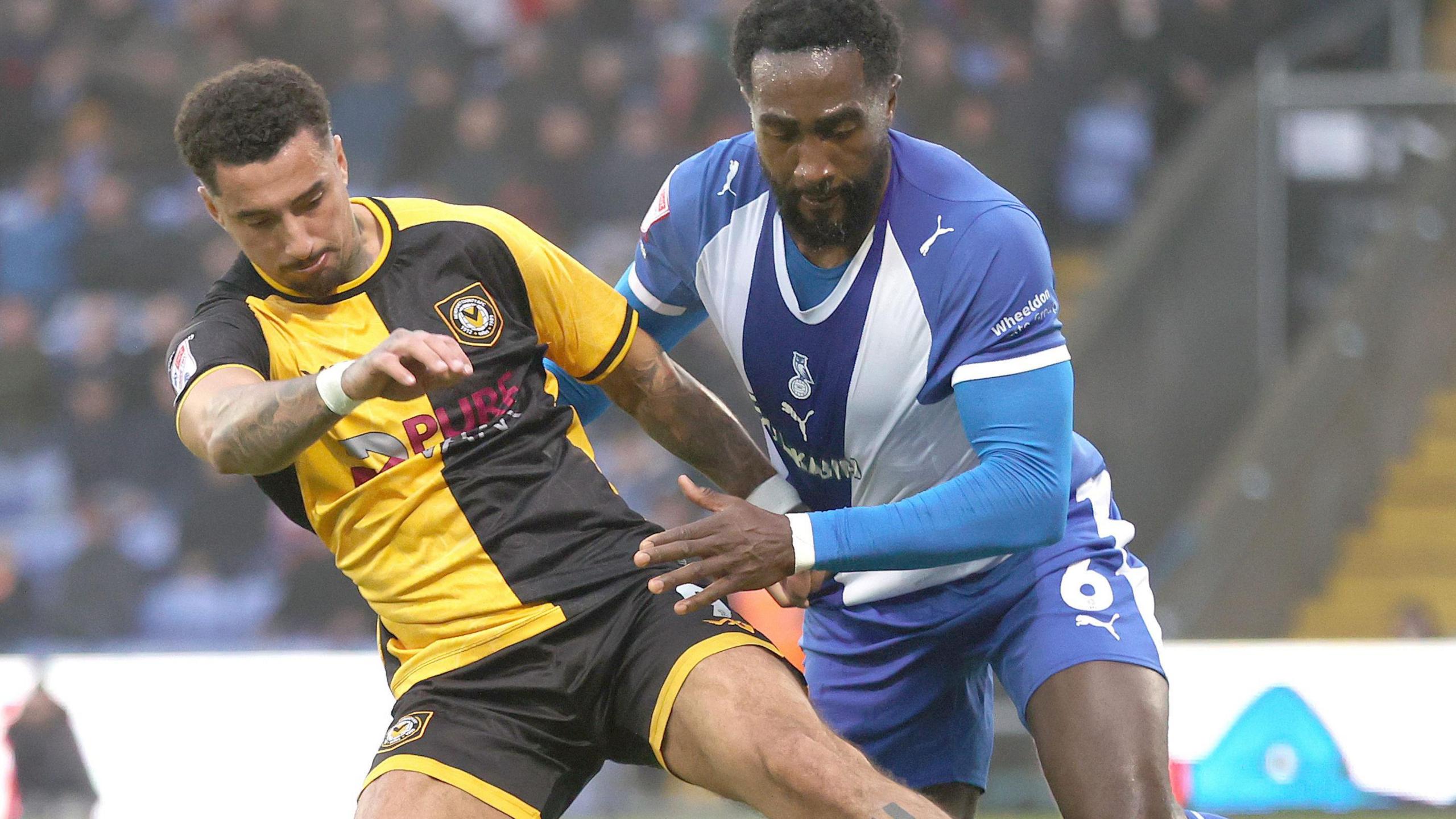 Newport's Courtney Baker-Richardson battles for the ball with Oldham's Manny Monthe