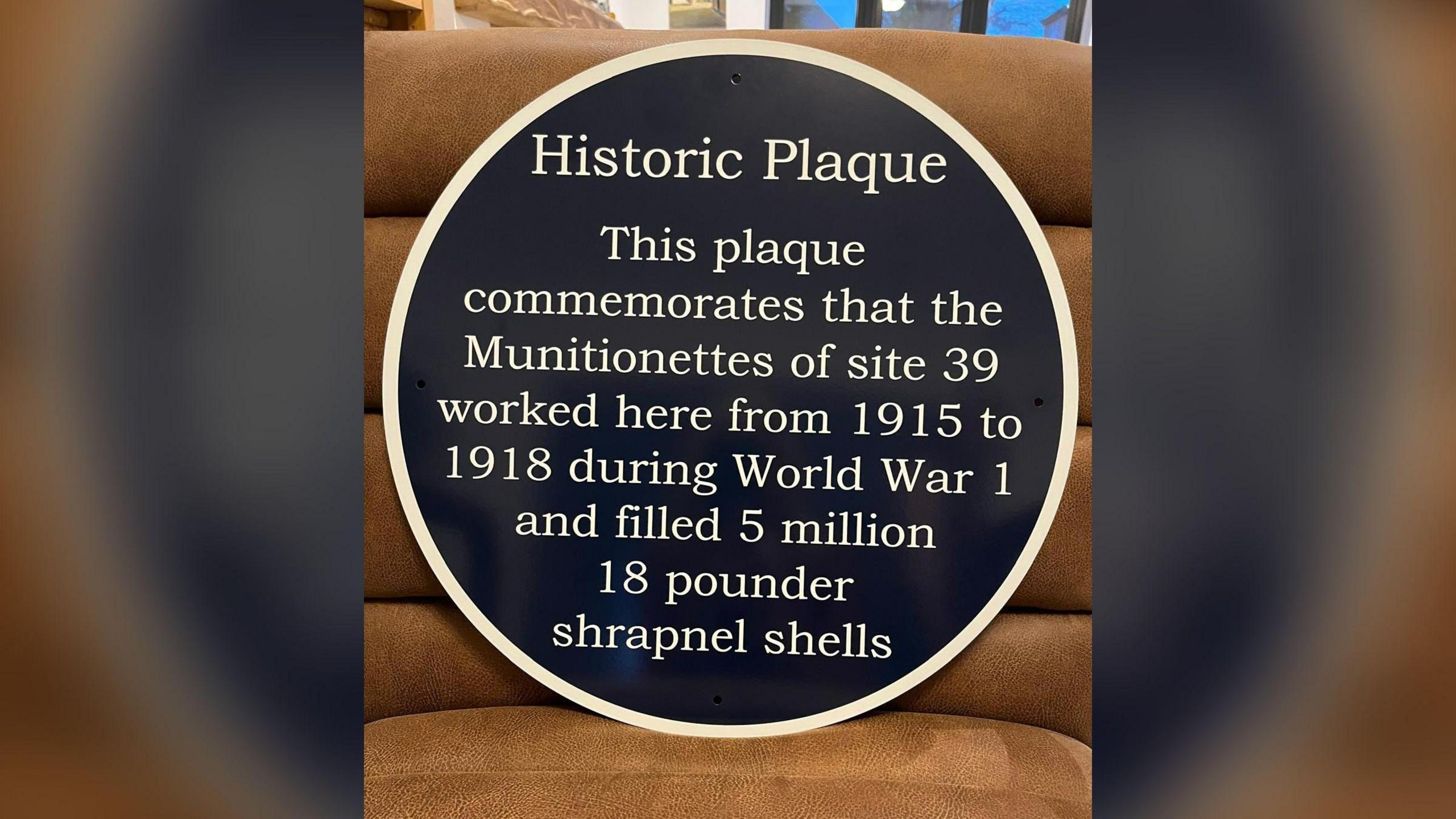 A blue plaque saying "This plaque commemorates that the Munitionettes of site 39 worked here from 1915 to 1918 during World War One and filled 5 million 18 pounder shrapnel shells."