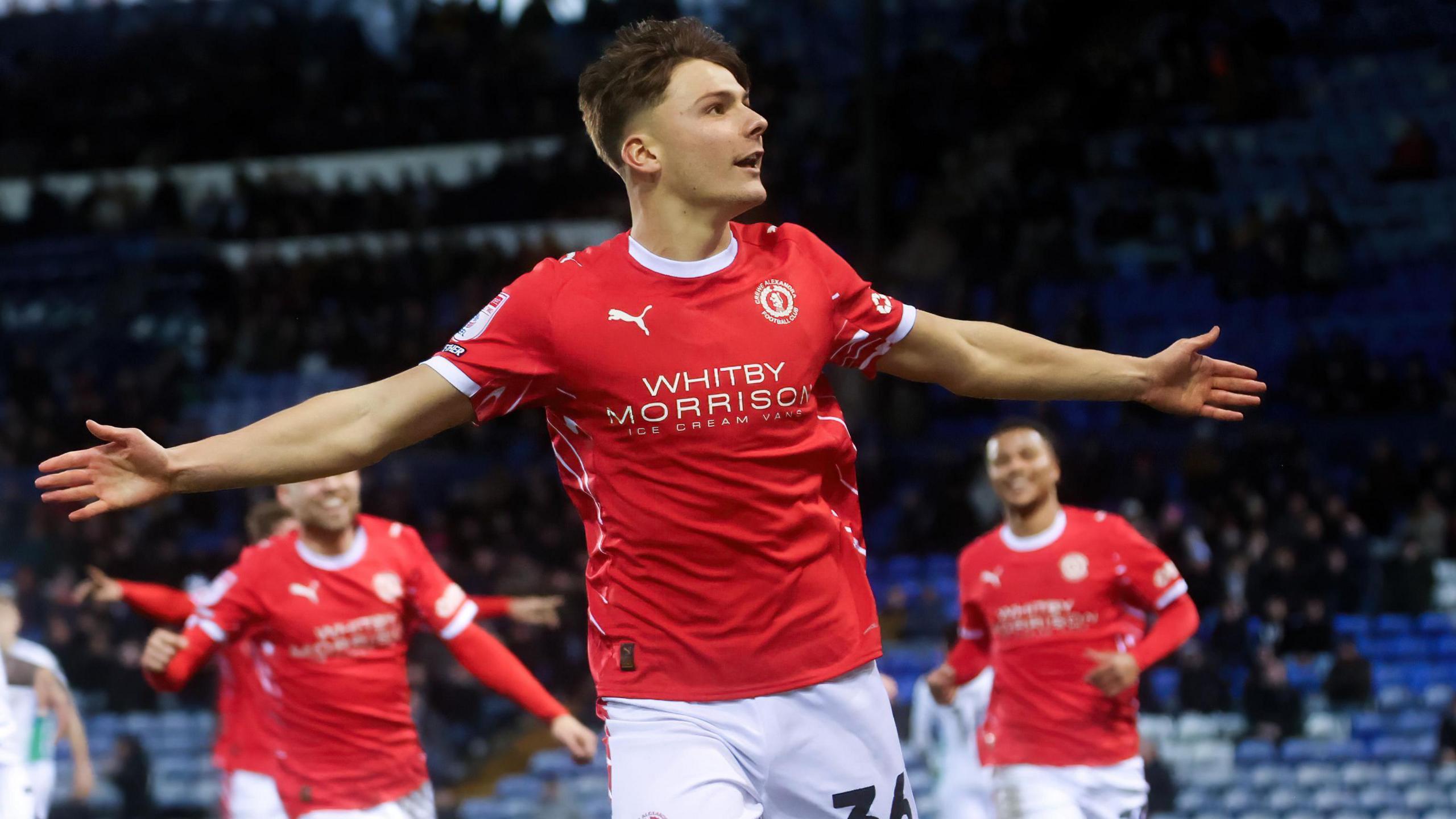 Emre Tezgel holds his arms out in celebration after scoring for Crewe