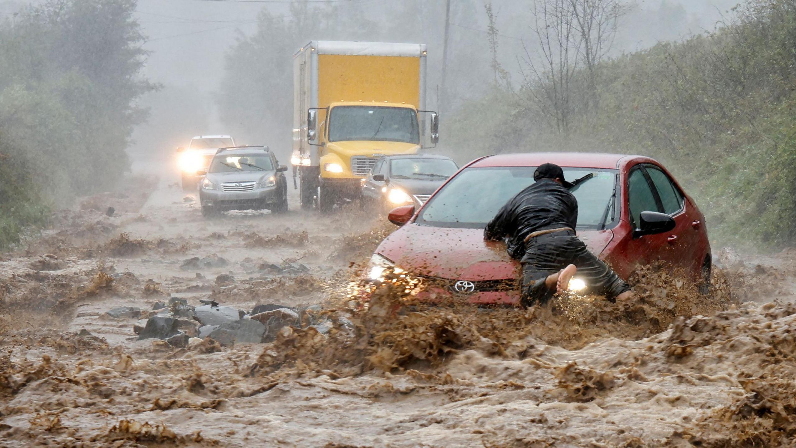 A local resident helps free a car that became stranded in a stretch of flooding road on the outskirts of Boone, North Carolina.