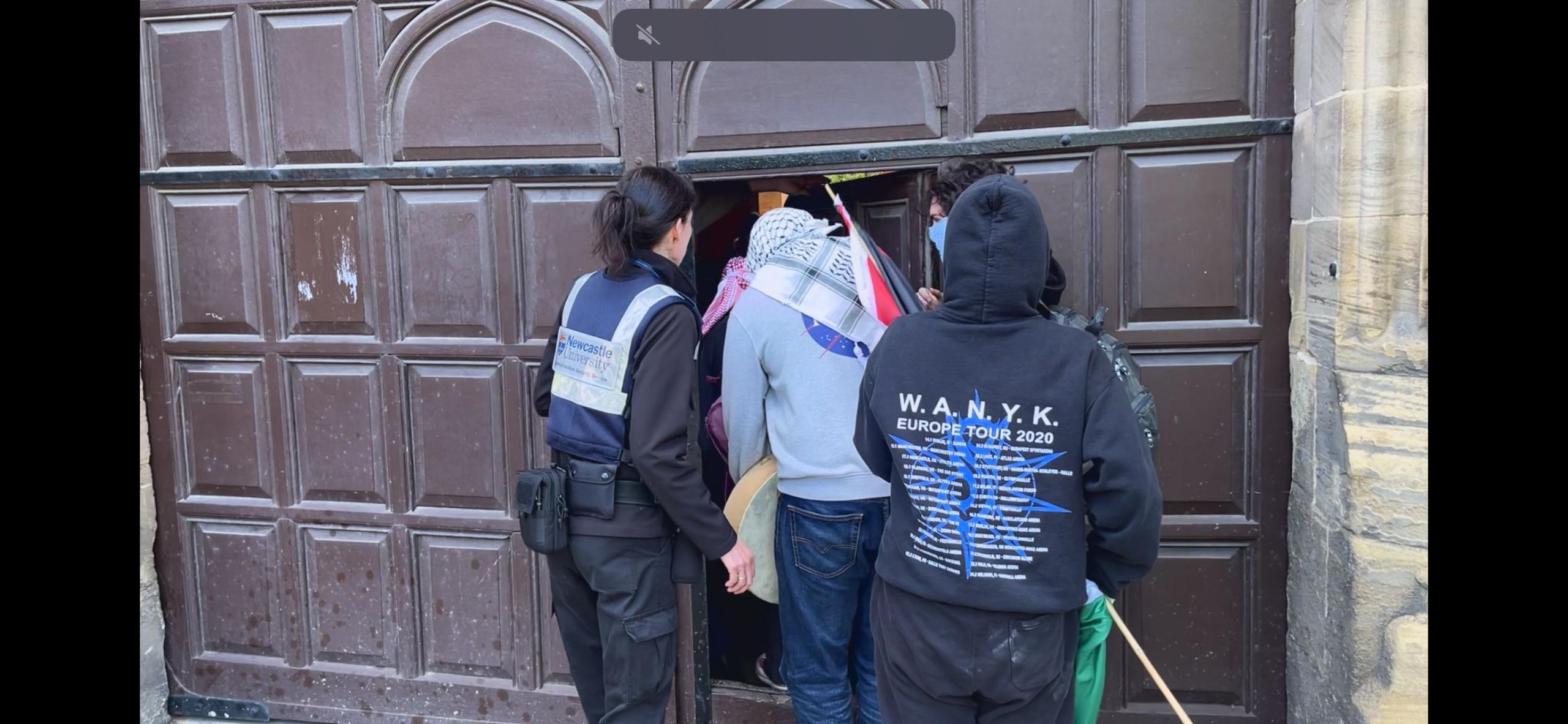 A security guard attempting to stop protesters entering the Newcastle University Armstrong Building