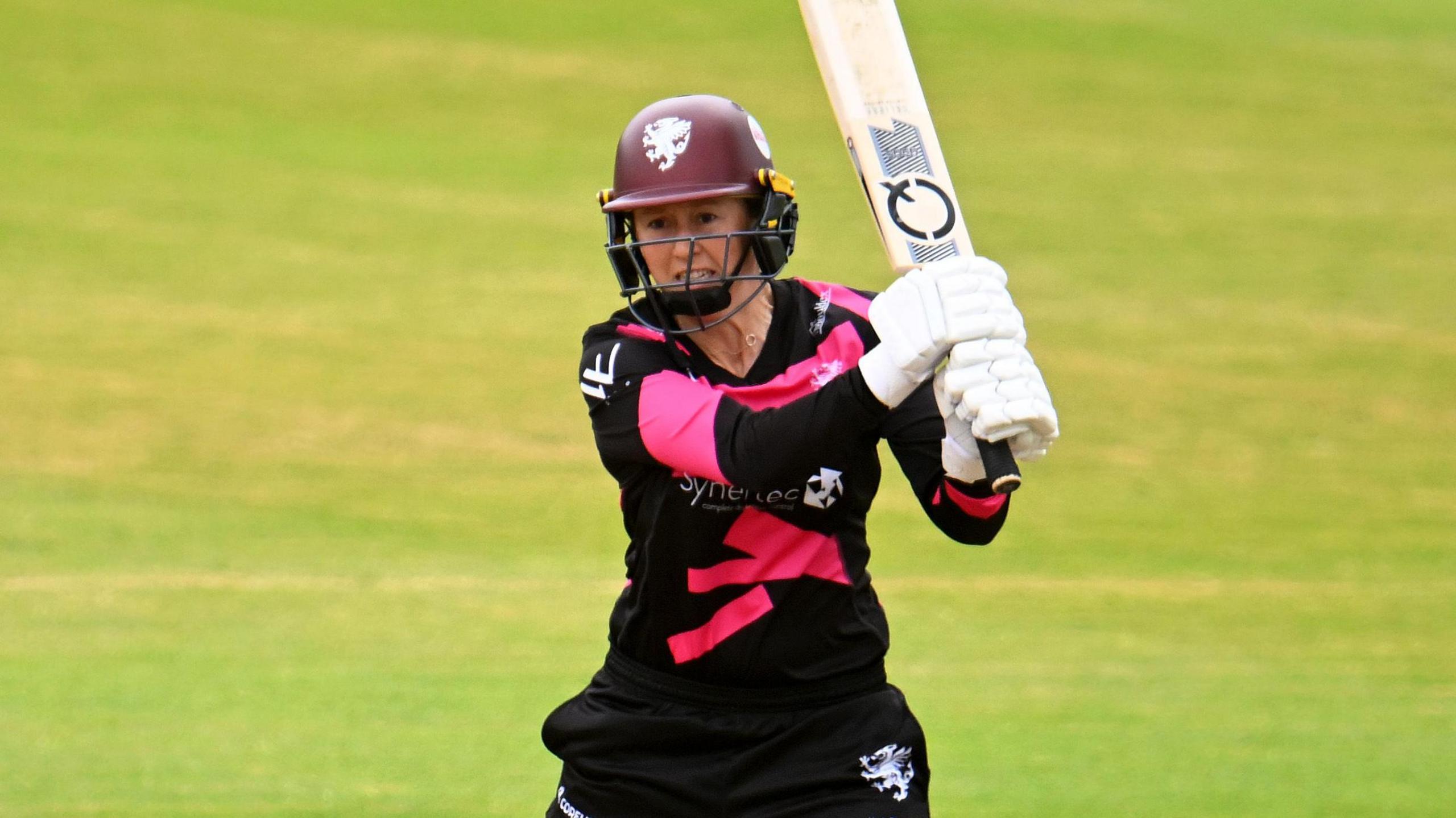 Fran Wilson holding the bat in the air with two hands during a match