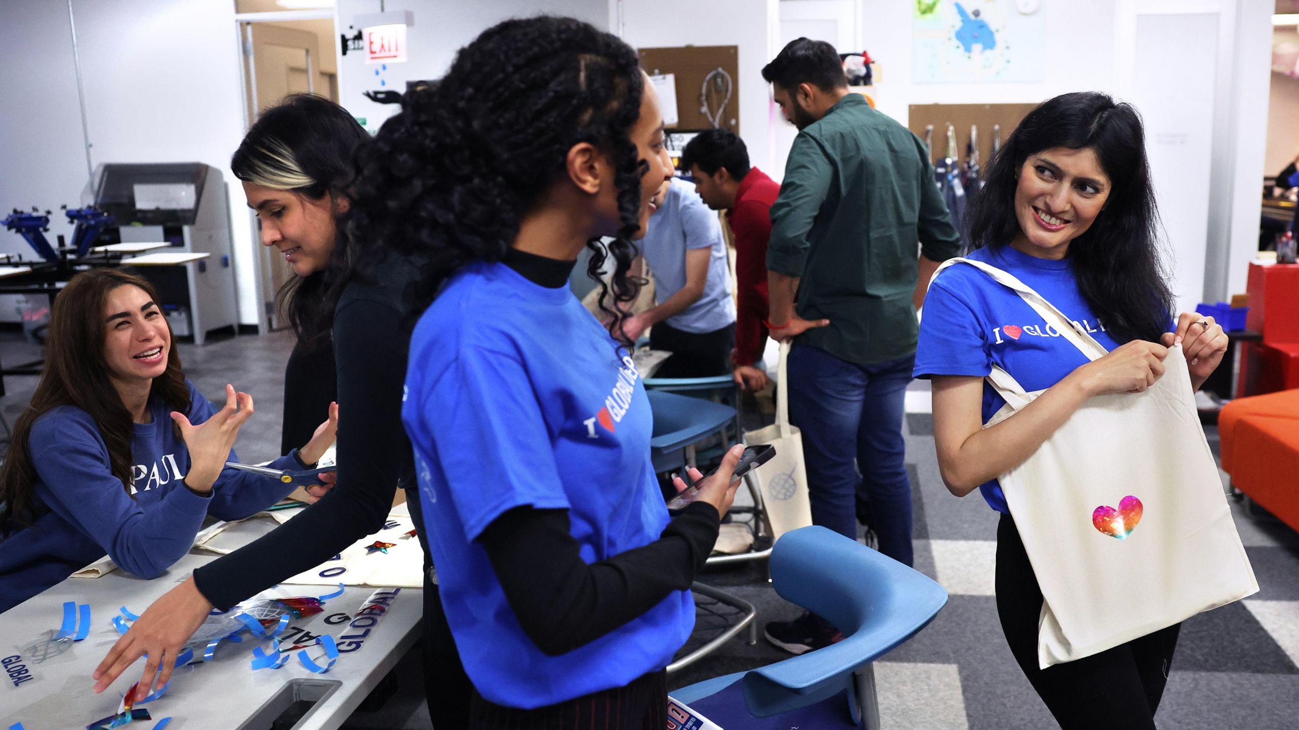DePaul University students Beemnet Desta of Ethiopia, middle, and Suchita Farkiwala of India, right, talk after making tote bags at a social gathering for international students at the school's downtown Chicago campus on Jan. 26, 2024.