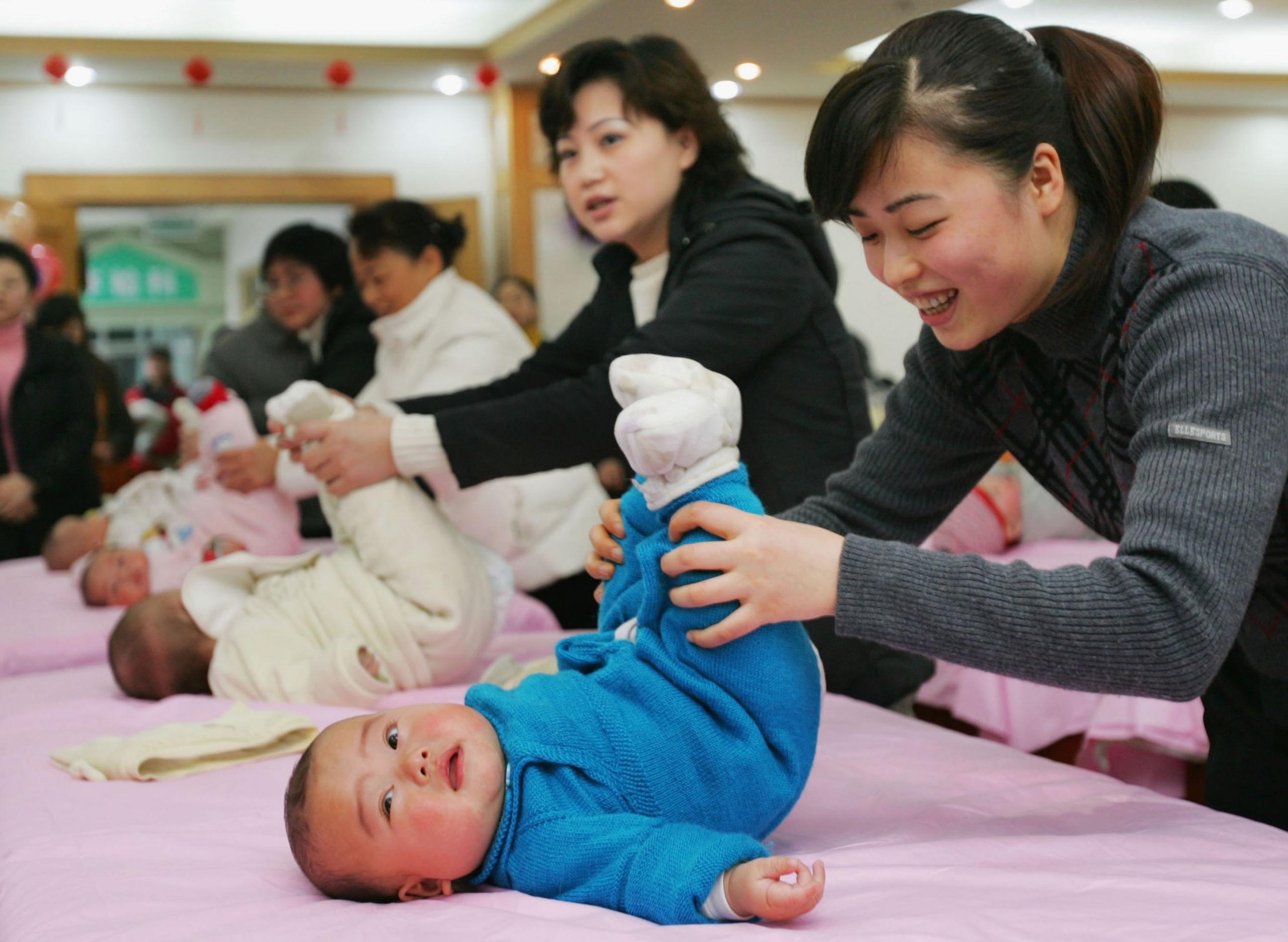 Mothers help babies do exercises during a 'Baby Gym Match' at the Chengdu Maternity Hospital