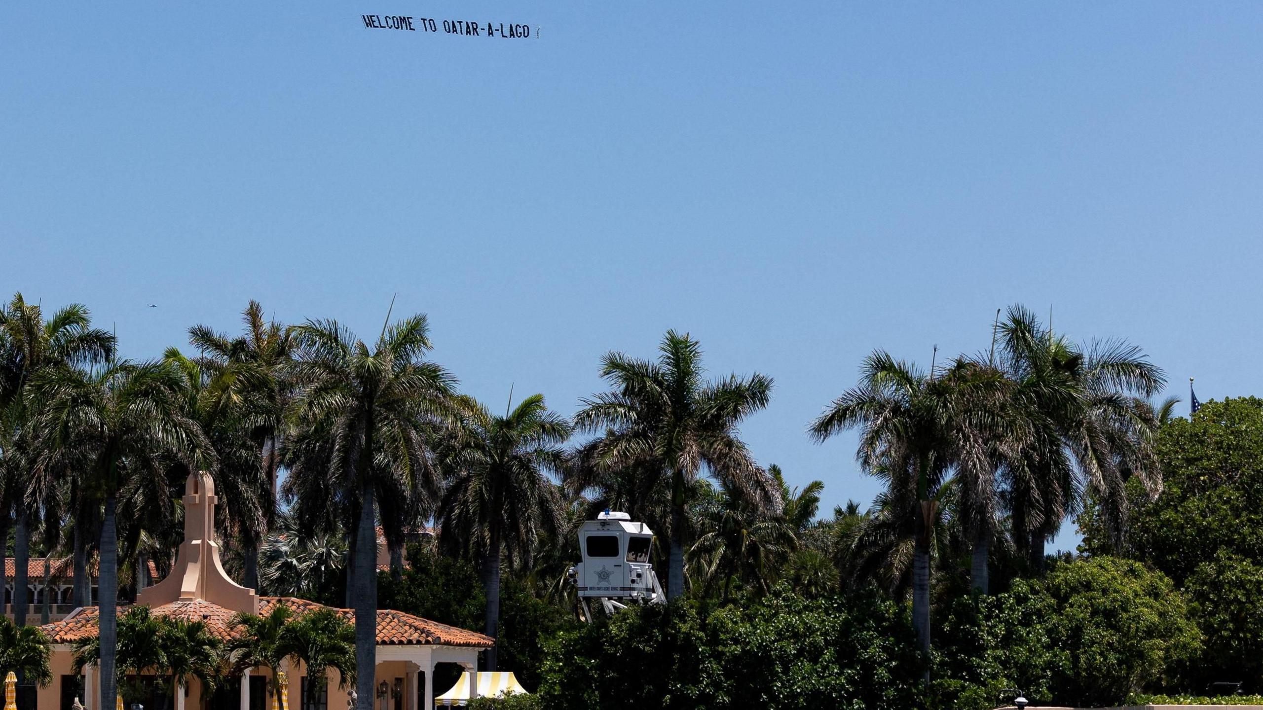 A plane flying a flat above Mar-a-Lago displaying writing reading 'Welcome to Qatar-a-Lago'