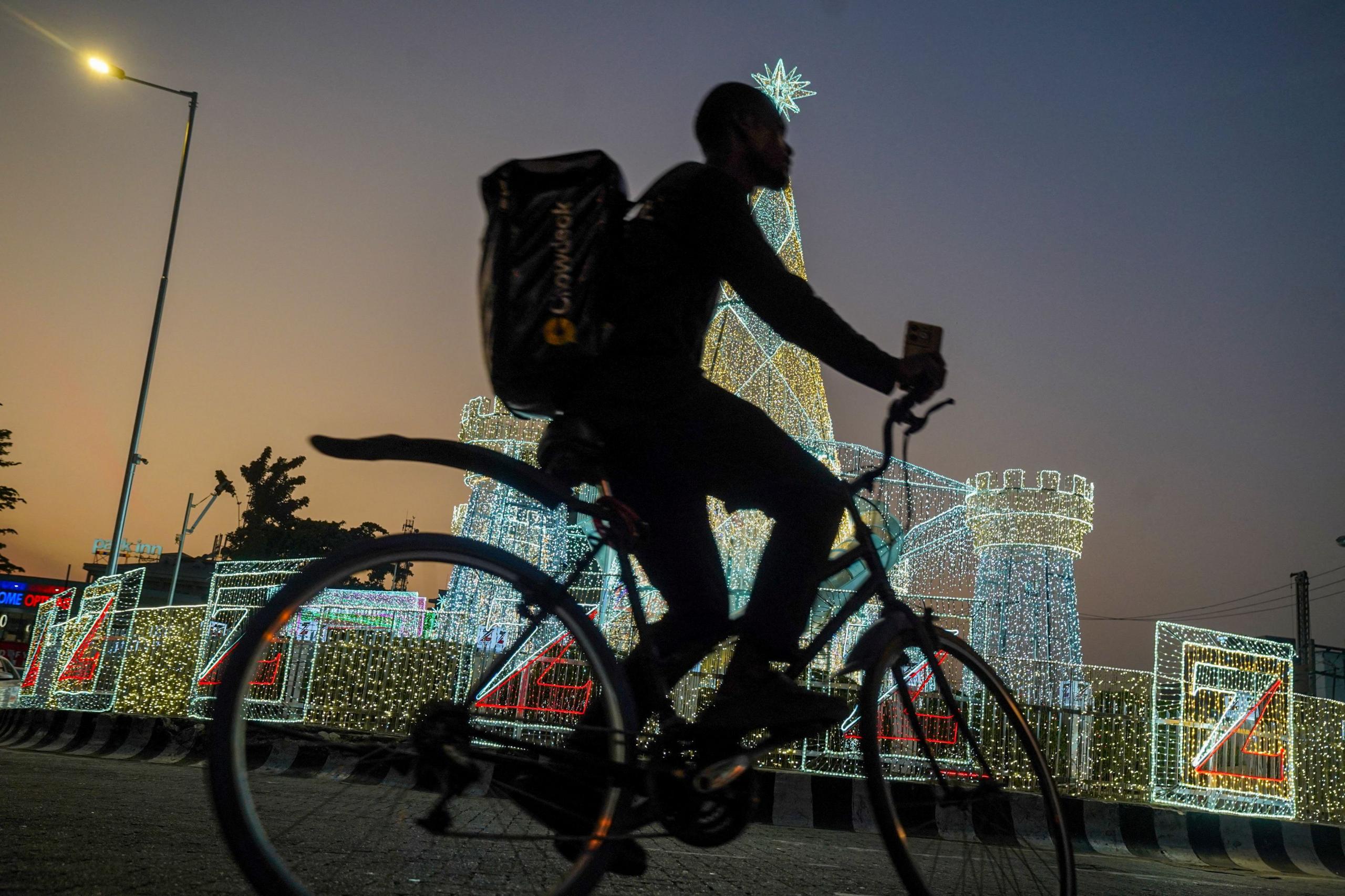 A cyclist passes illuminated Christmas lights.