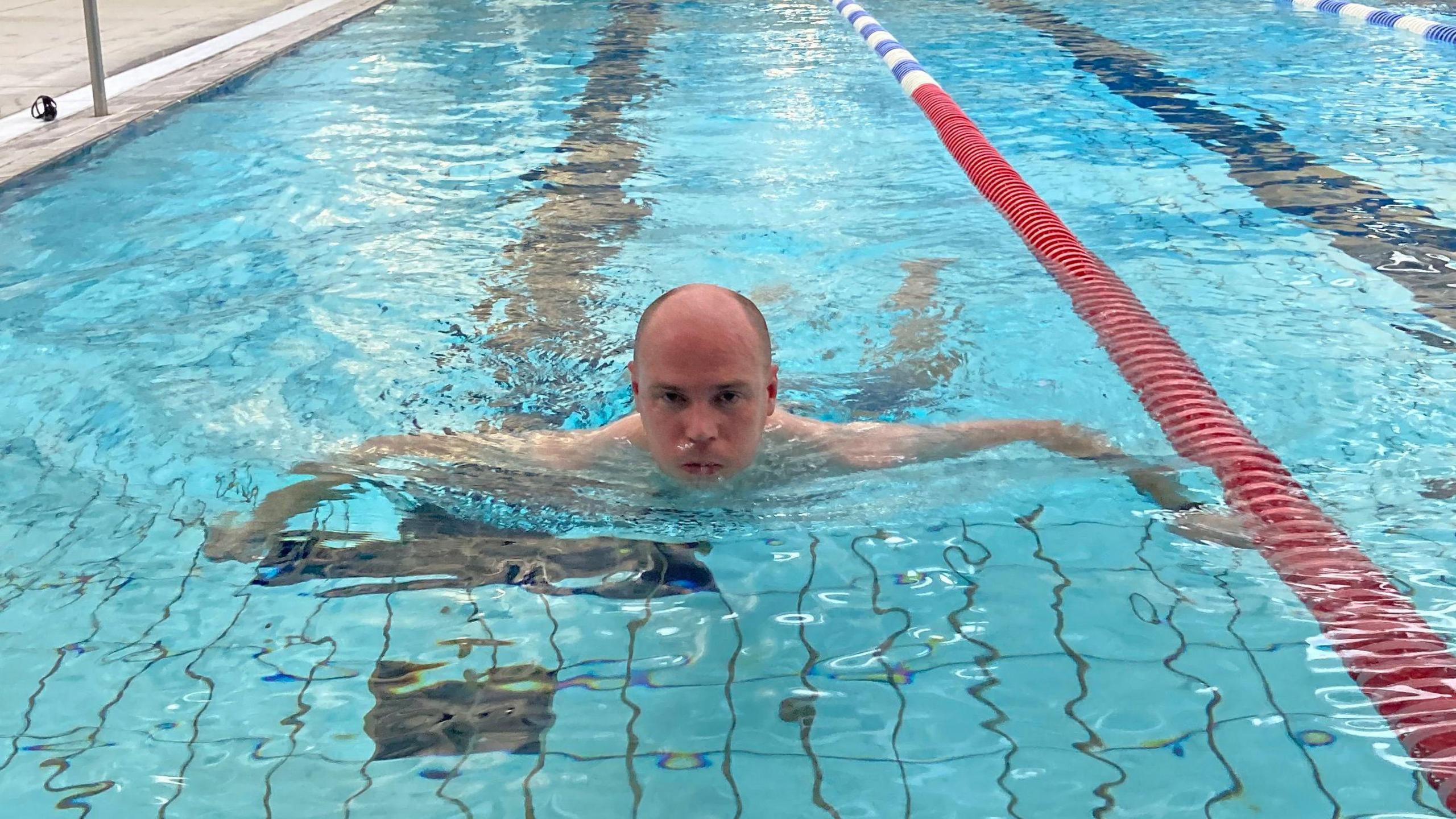 Dan swims breaststroke towards the camera, a steely determination on his face.