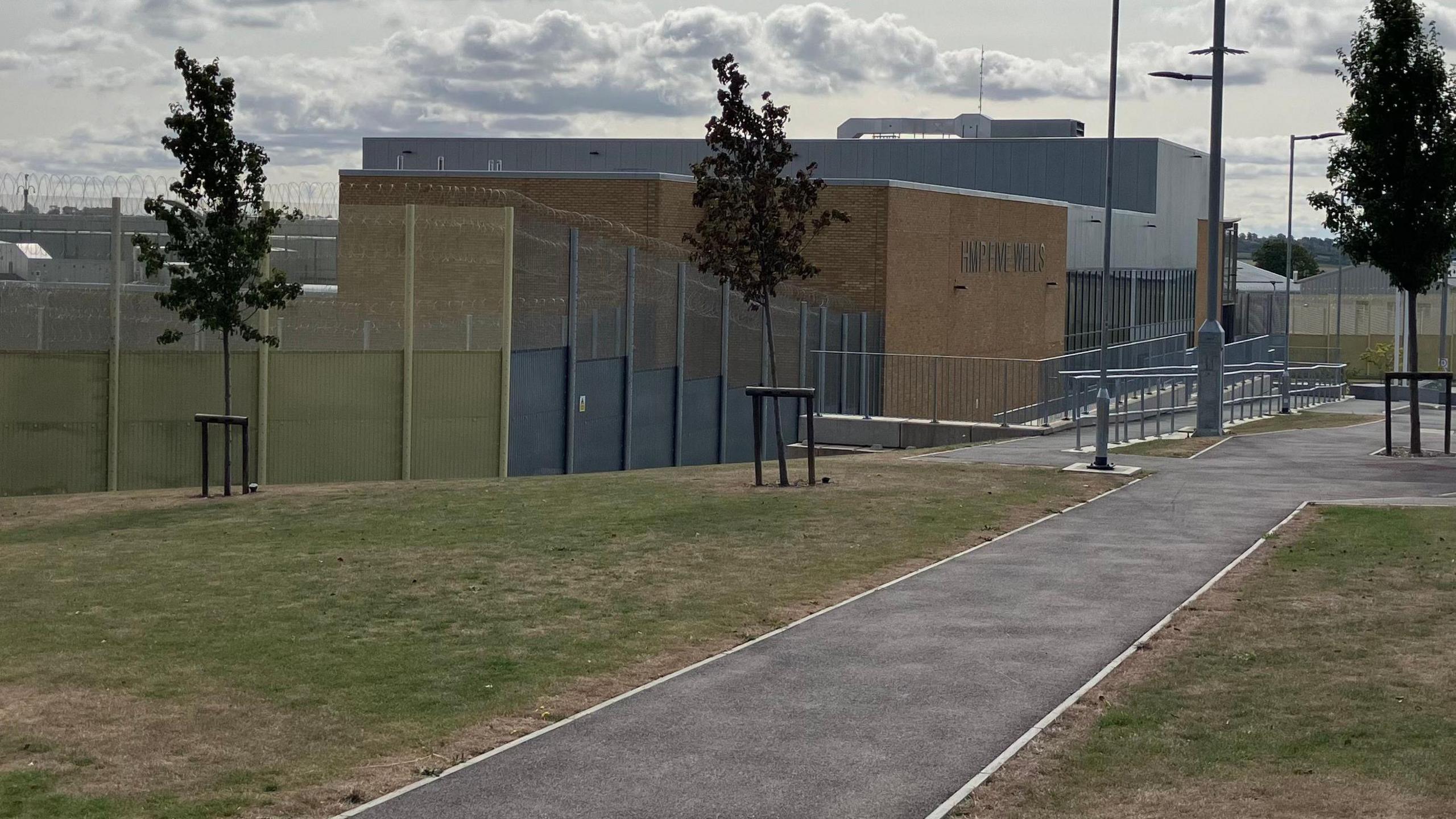 The outside of a prison building with high barbed wire fencing. 