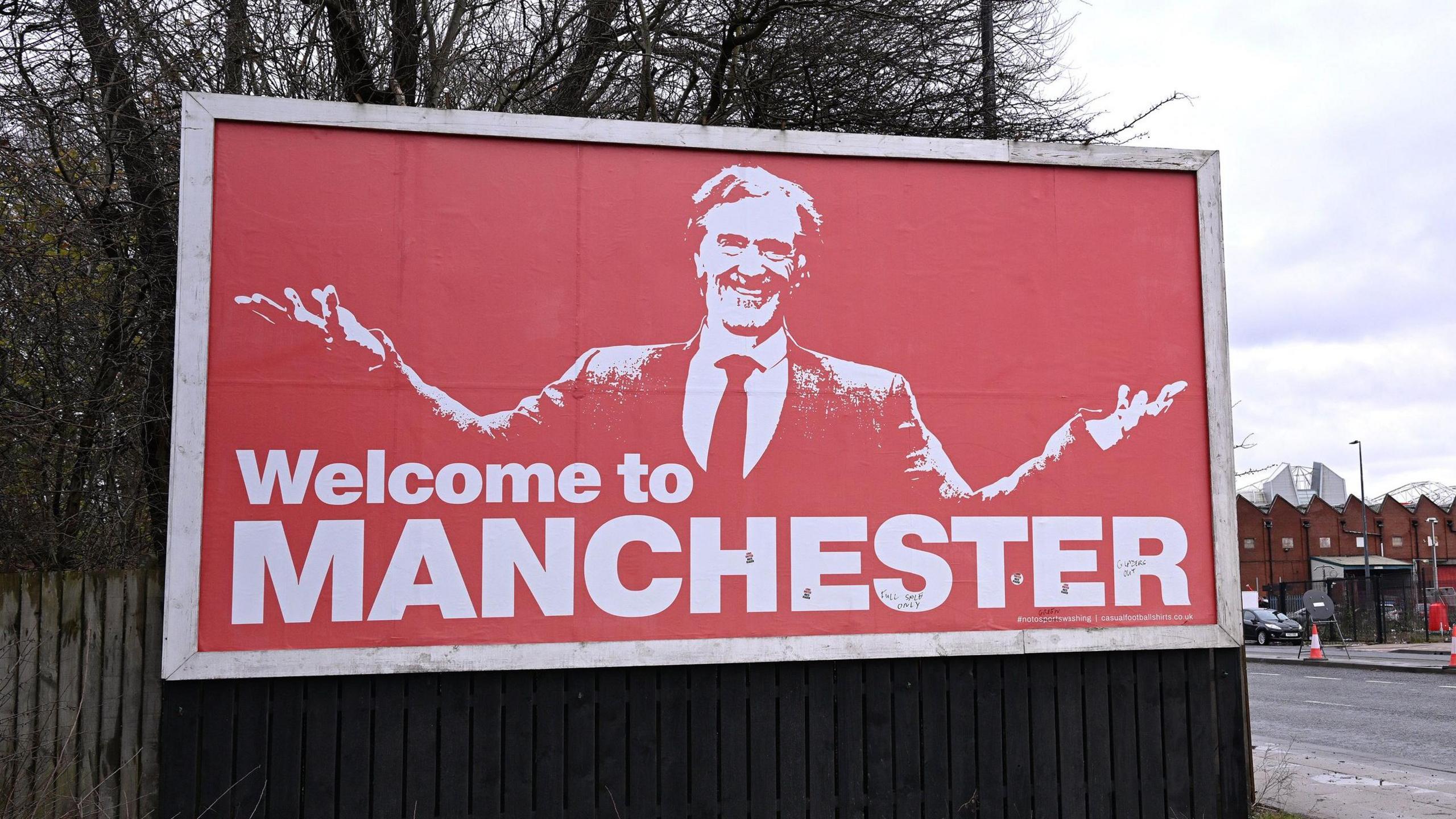 A billboard near Old Trafford featuring Sir Jim Ratcliffe and the words 'Welcome to Manchester'