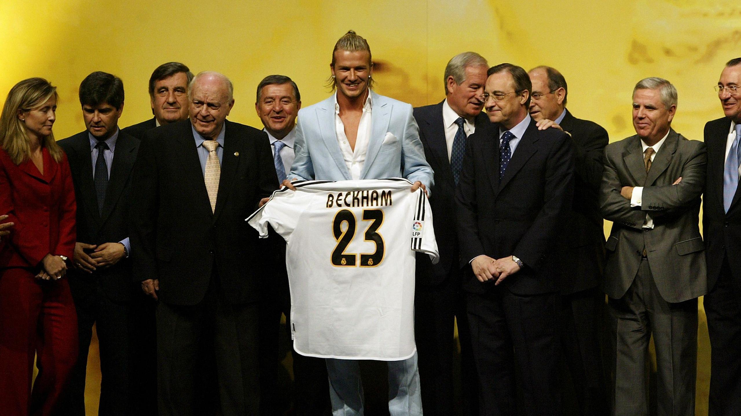David Beckham holds a 'Beckham 23' Real Madrid shirt after signing for the club, surrounded by club personnel