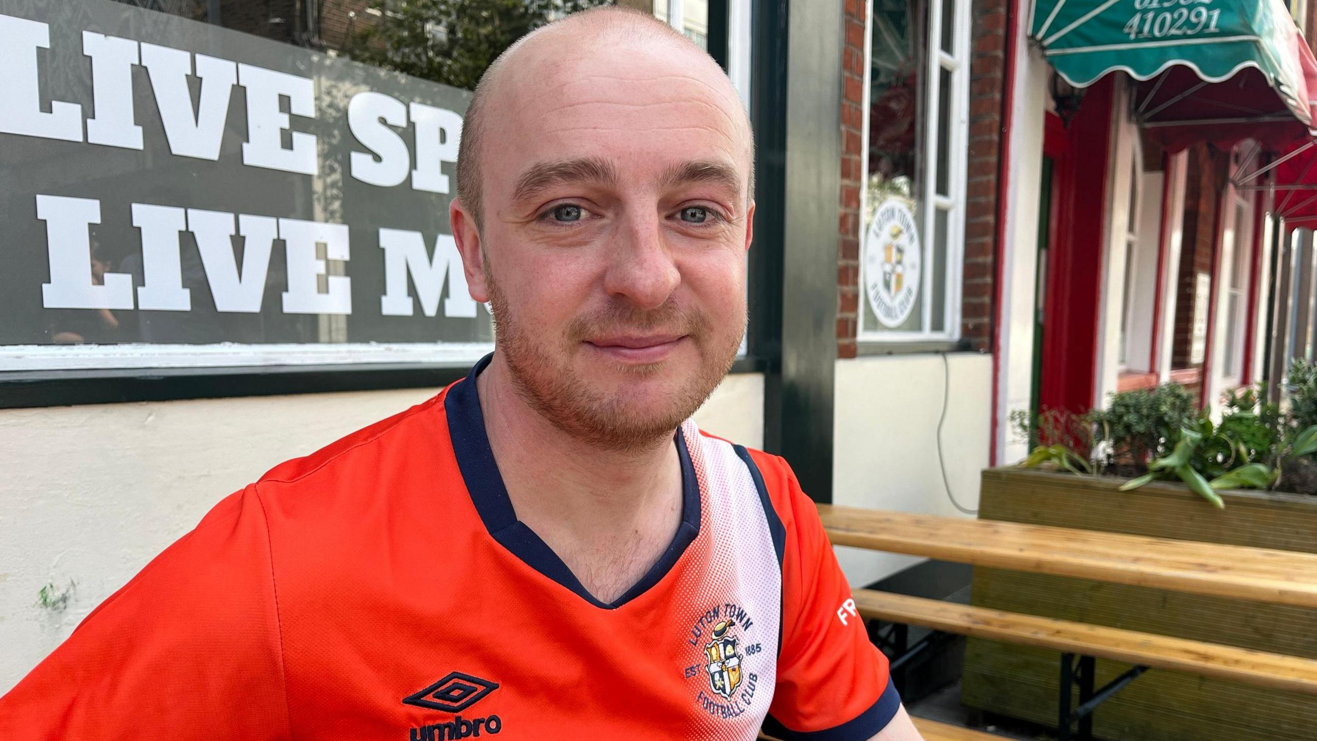 Jack O'Shea with very short brown hair and beard wearing a Luton shirt