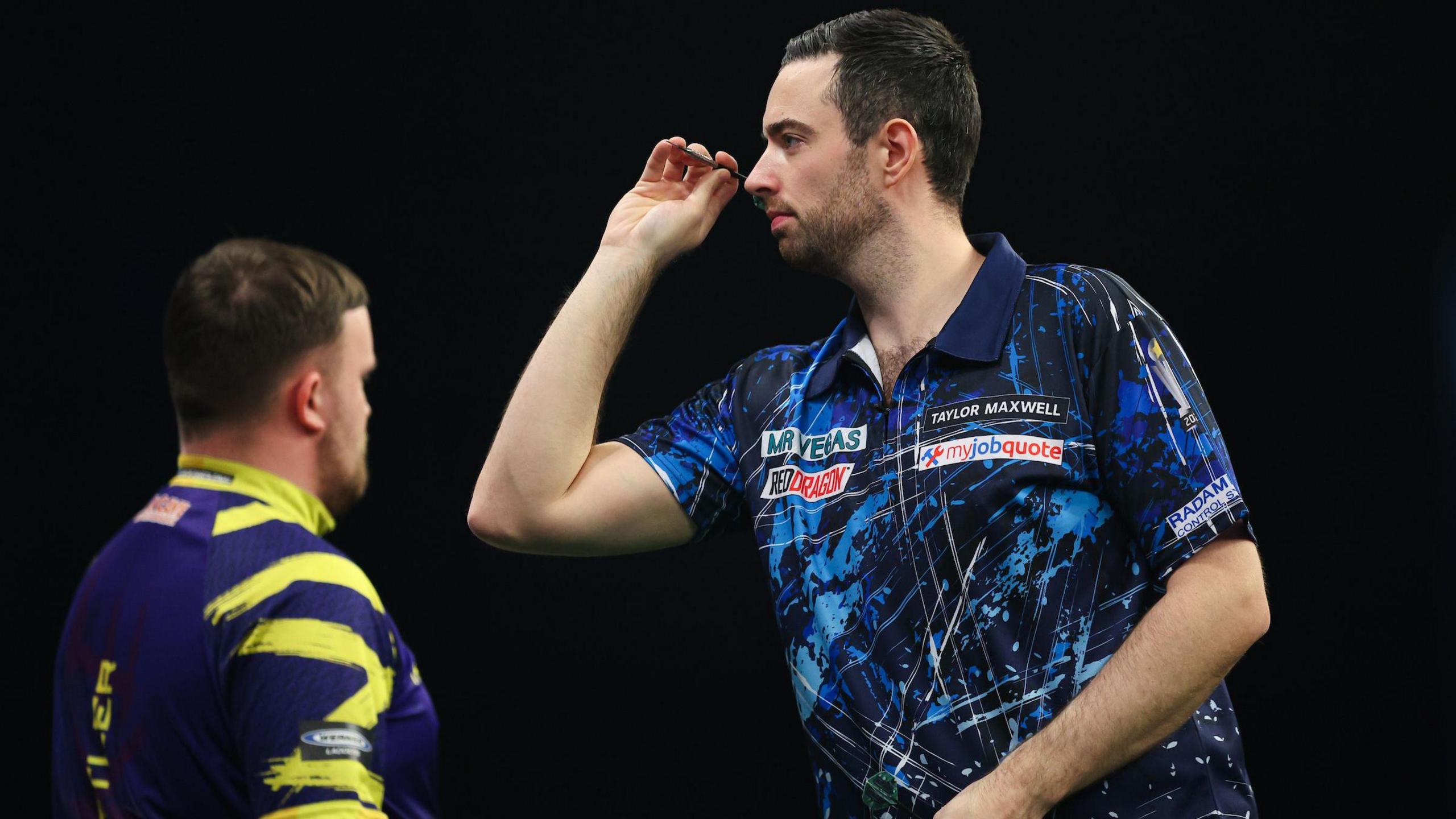 Luke Humphries throws with Luke Littler in the background