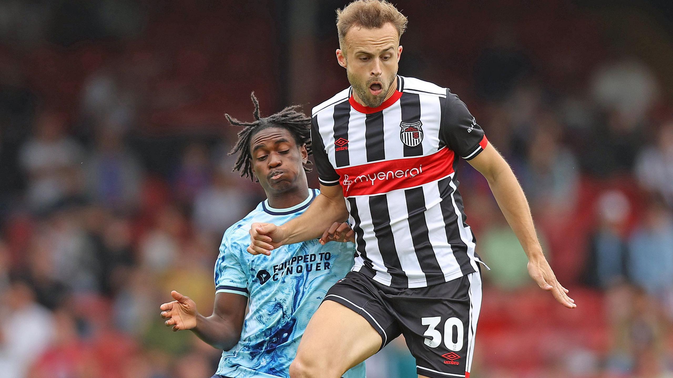 Habeeb Ogunneye of Newport County challenges Grimsby's Charles Vernam for the ball