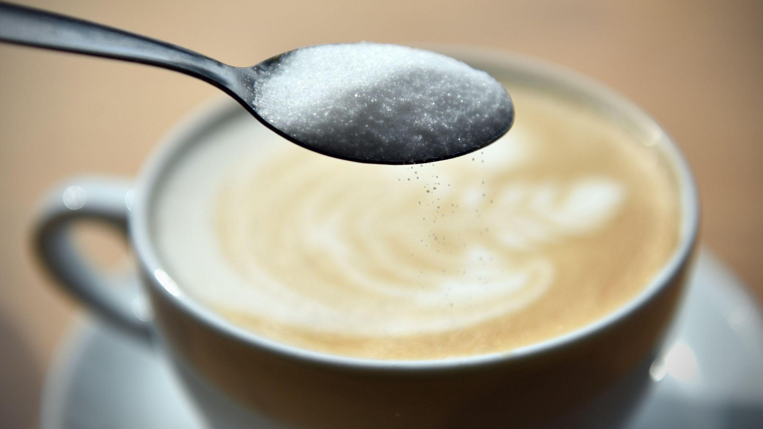 Spoon of sugar over coffee cup