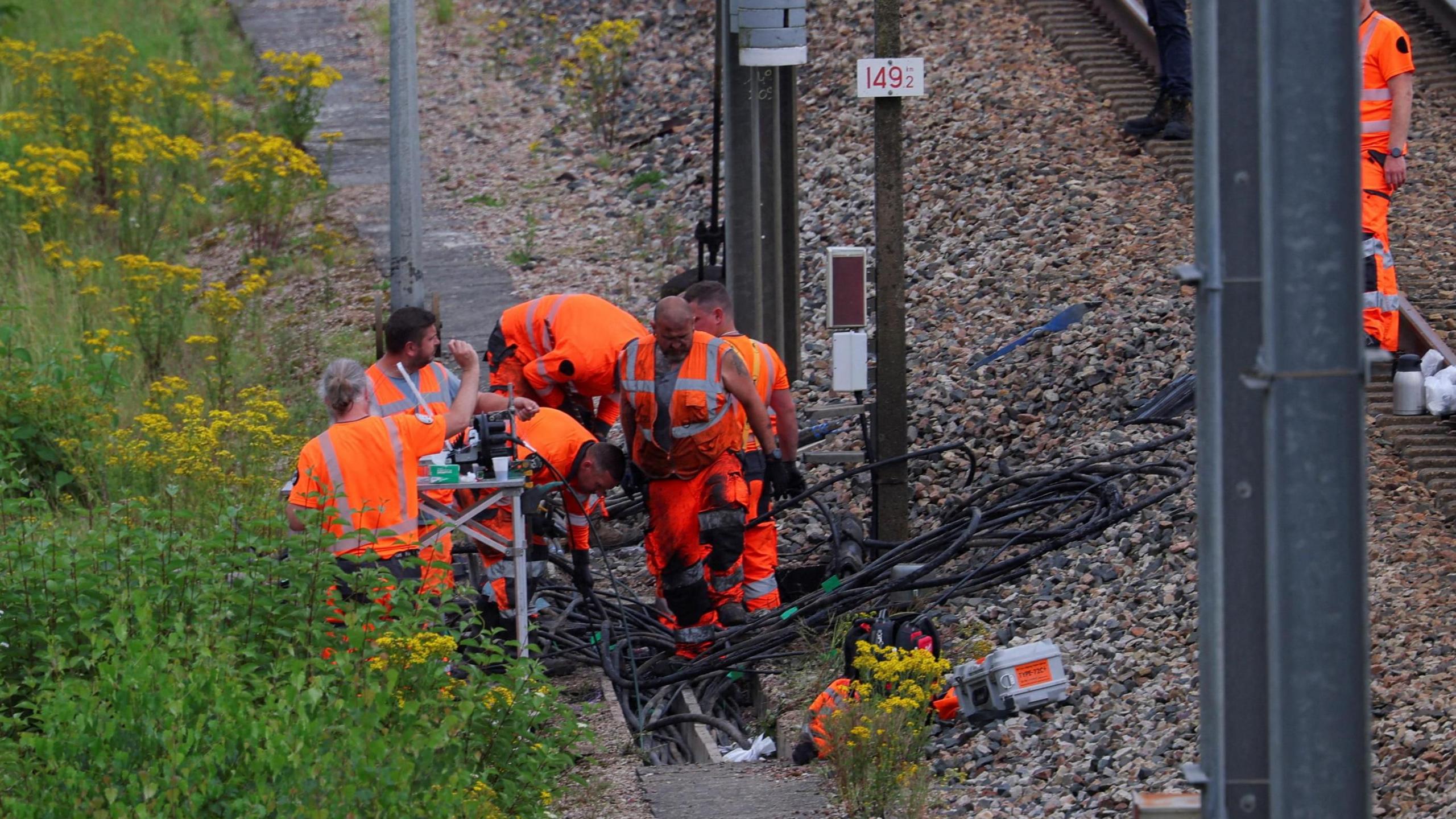 SNCF railway workers and law enforcement officers work at the site where vandals targeted France's high-speed train network