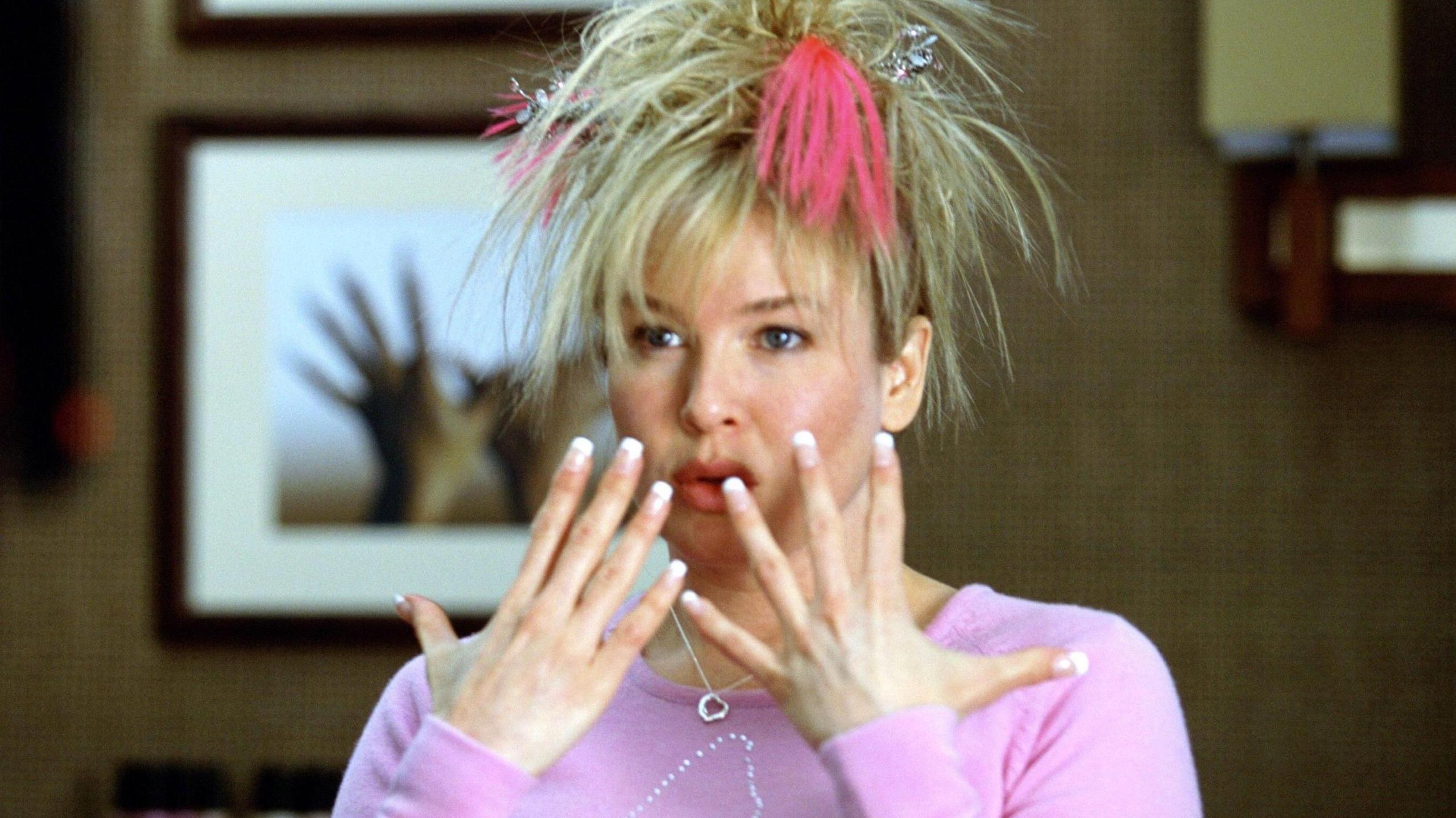 A still of Renee Zellweger as Bridget Jones, with messy hair and wearing a pink jumper