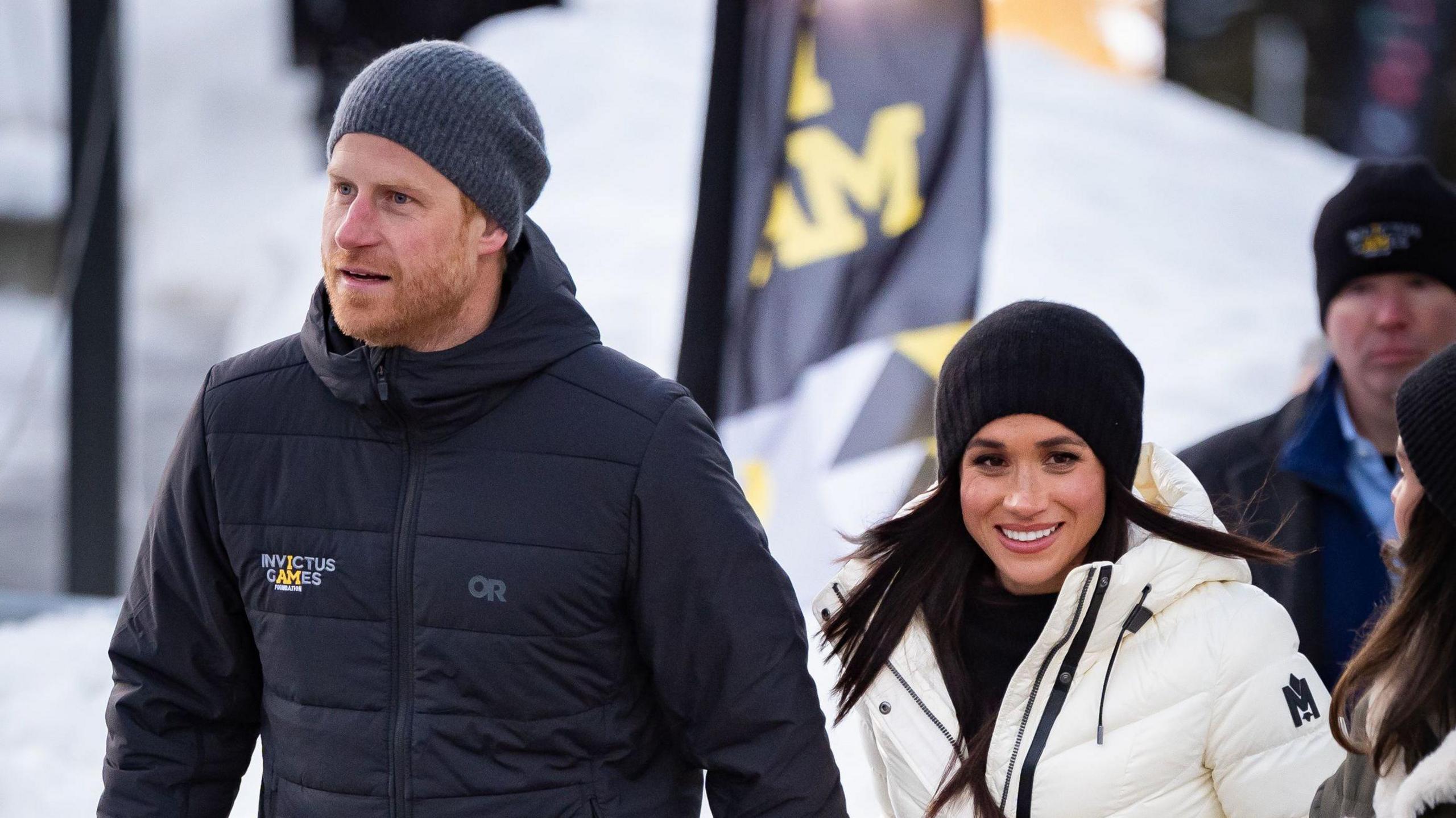 The Duke and Duchess of Sussex attending the 2025 Invictus Games in Vancouver this month. Harry is wearing a blue Invictus Games coat and woolly hat. Meghan is wearing a black woolly hat an white coat.