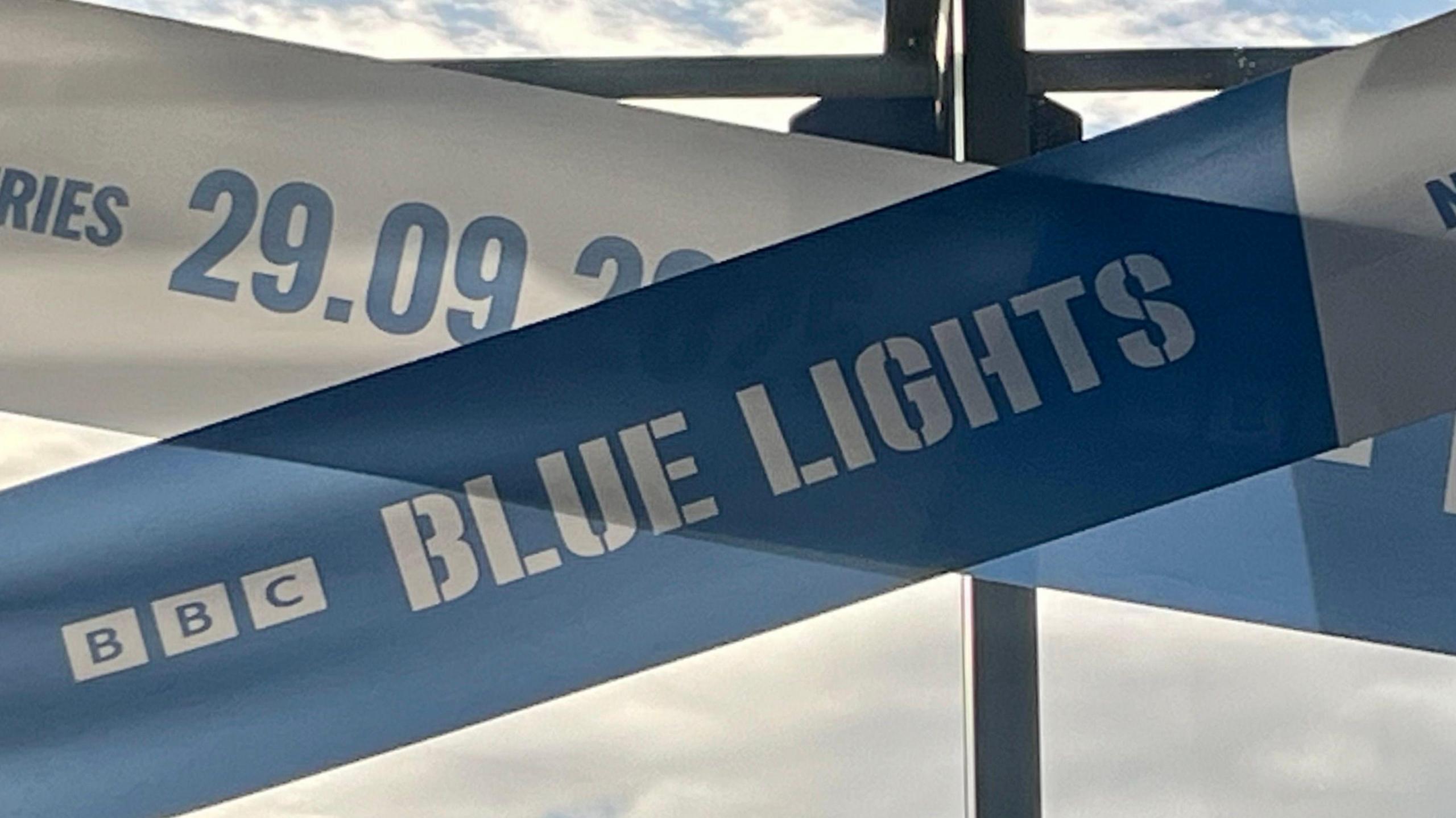 Large blue and white police tape showing 'BBC Blue Lights 29.09.25' is put up across the windows of Belfast's Grand Central Station.
