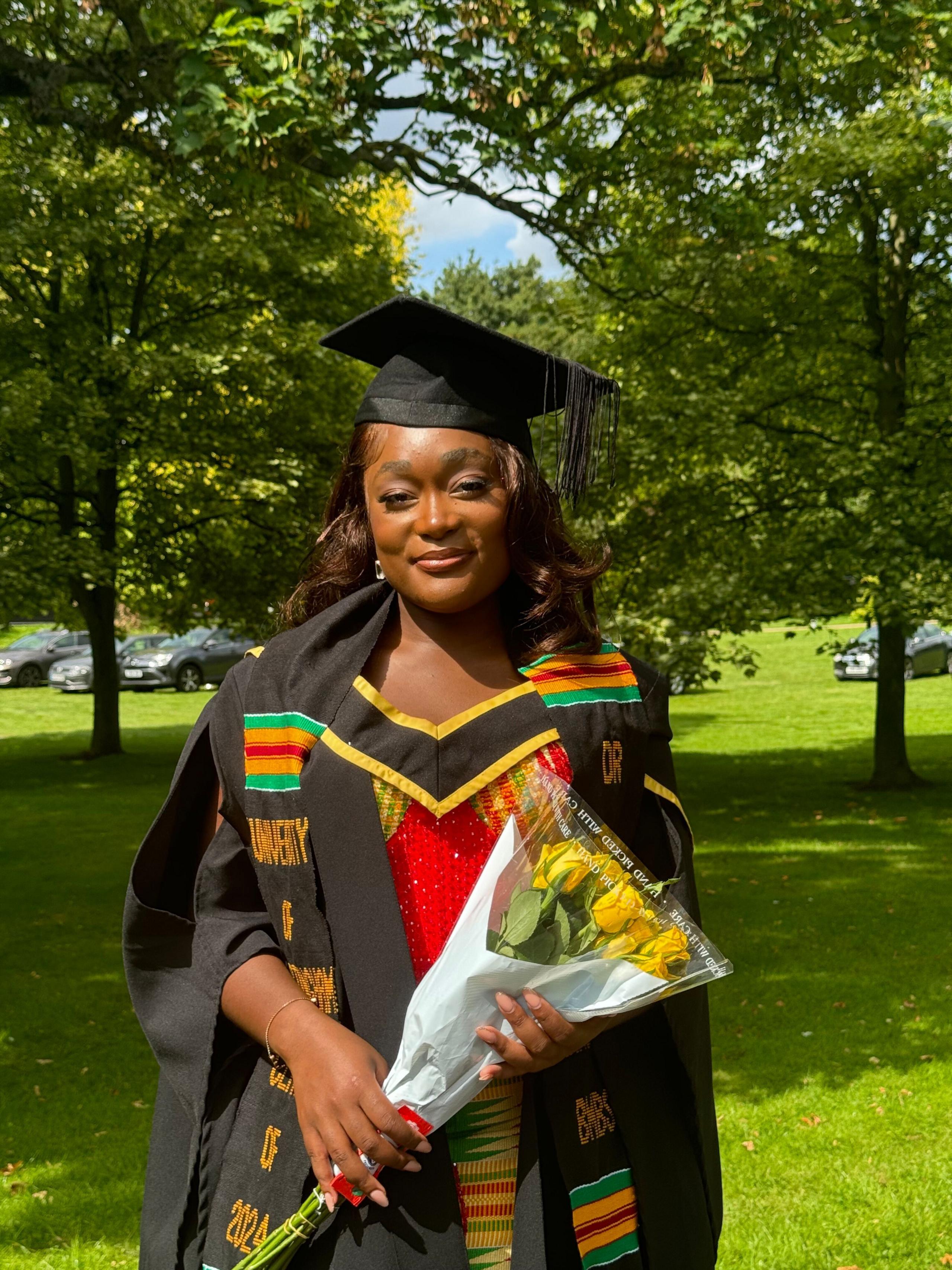 Dr Ntorinkansah following her graduation in her cap and gown and carrying a bunch of flowers