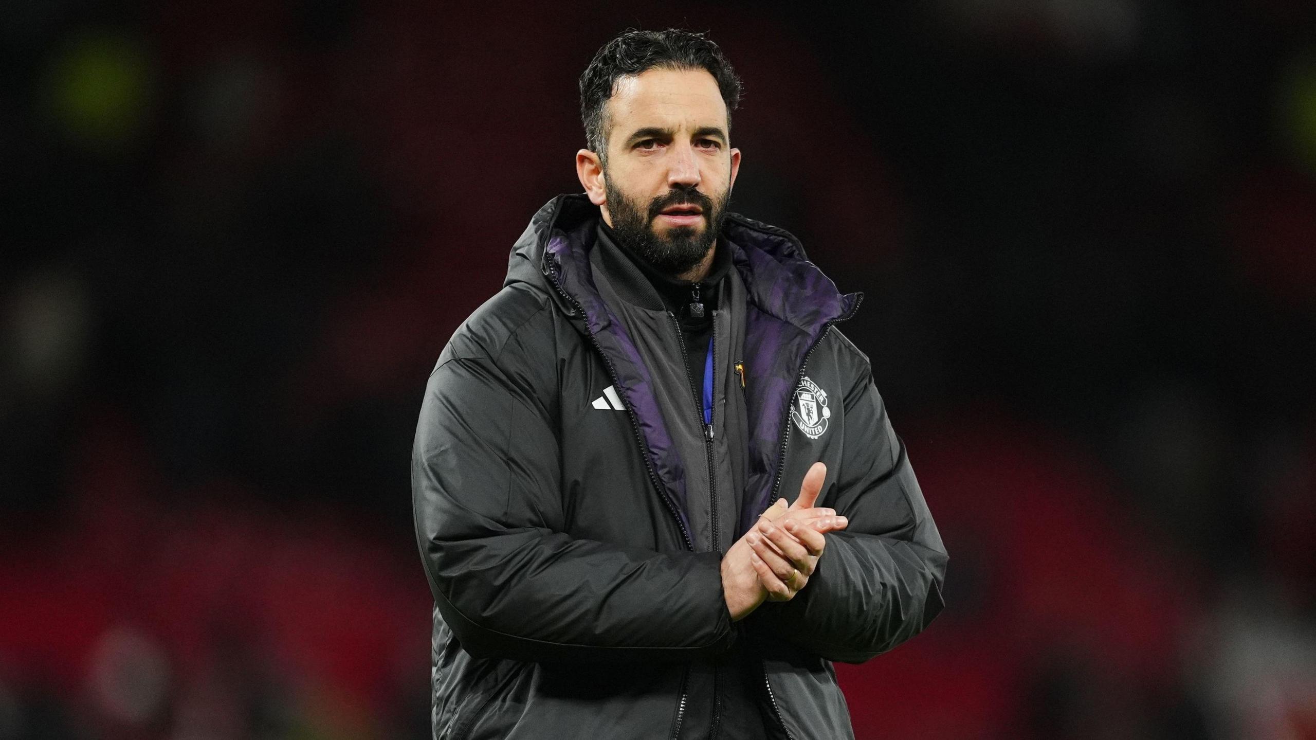 ruben aqmorim in a black puffer jacket on a football pitch.