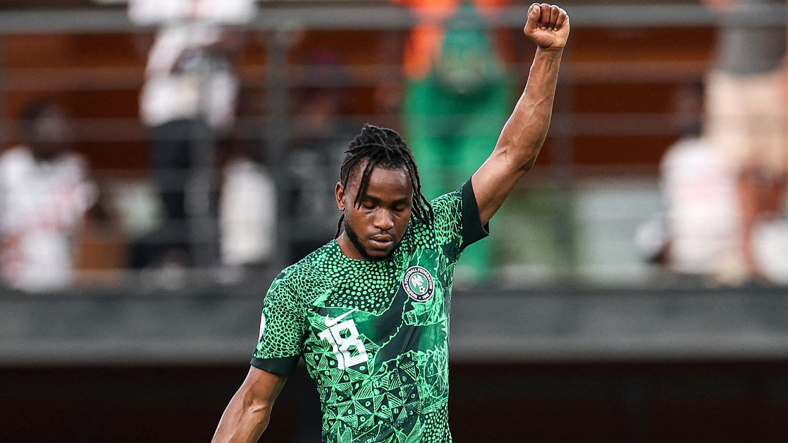 Ademola Lookman, wearing a green Nigeria shirt, raises his left arm with his fist clenched in celebration