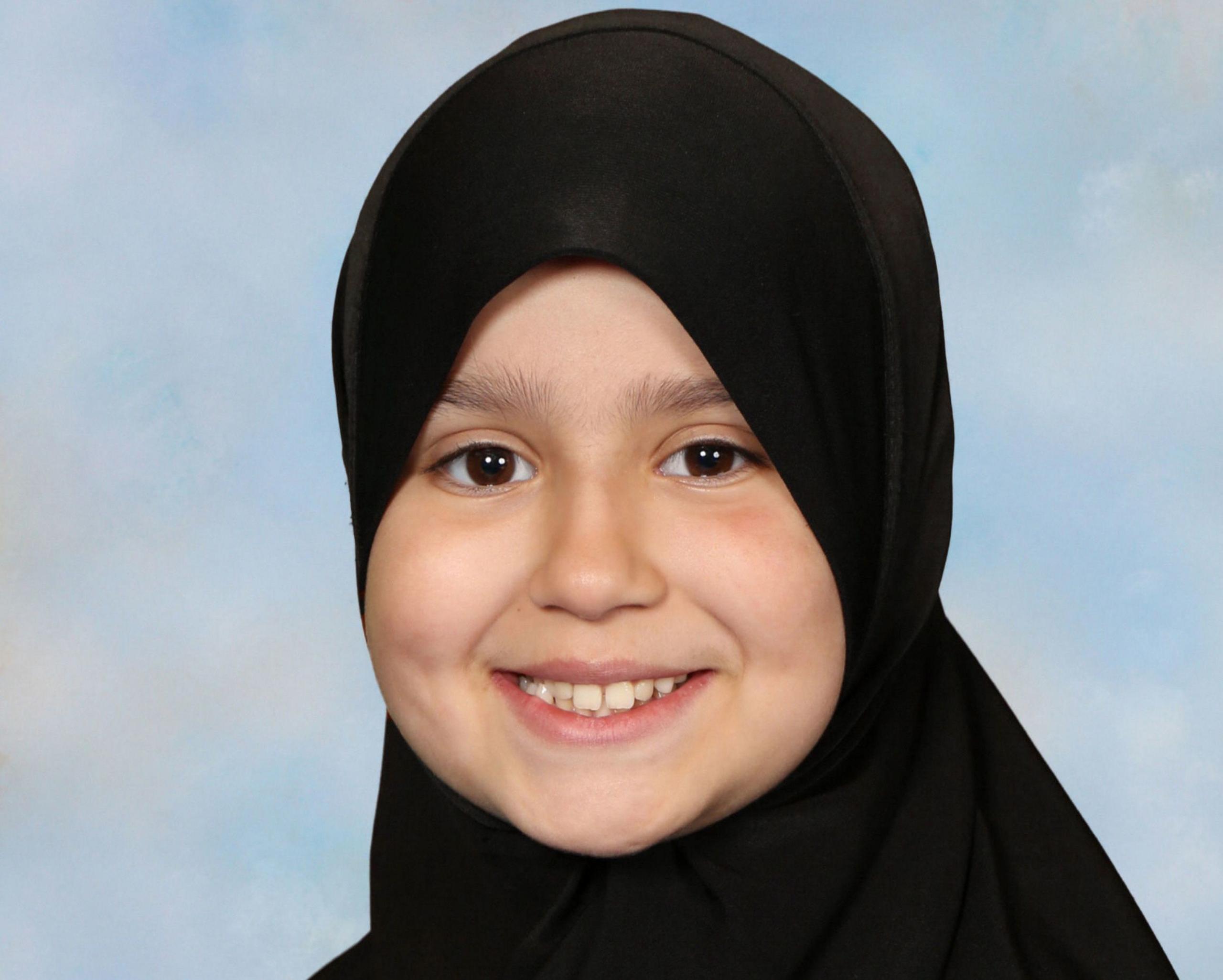 Sarah smiles looking directly at the camera. She is wearing a black hijab