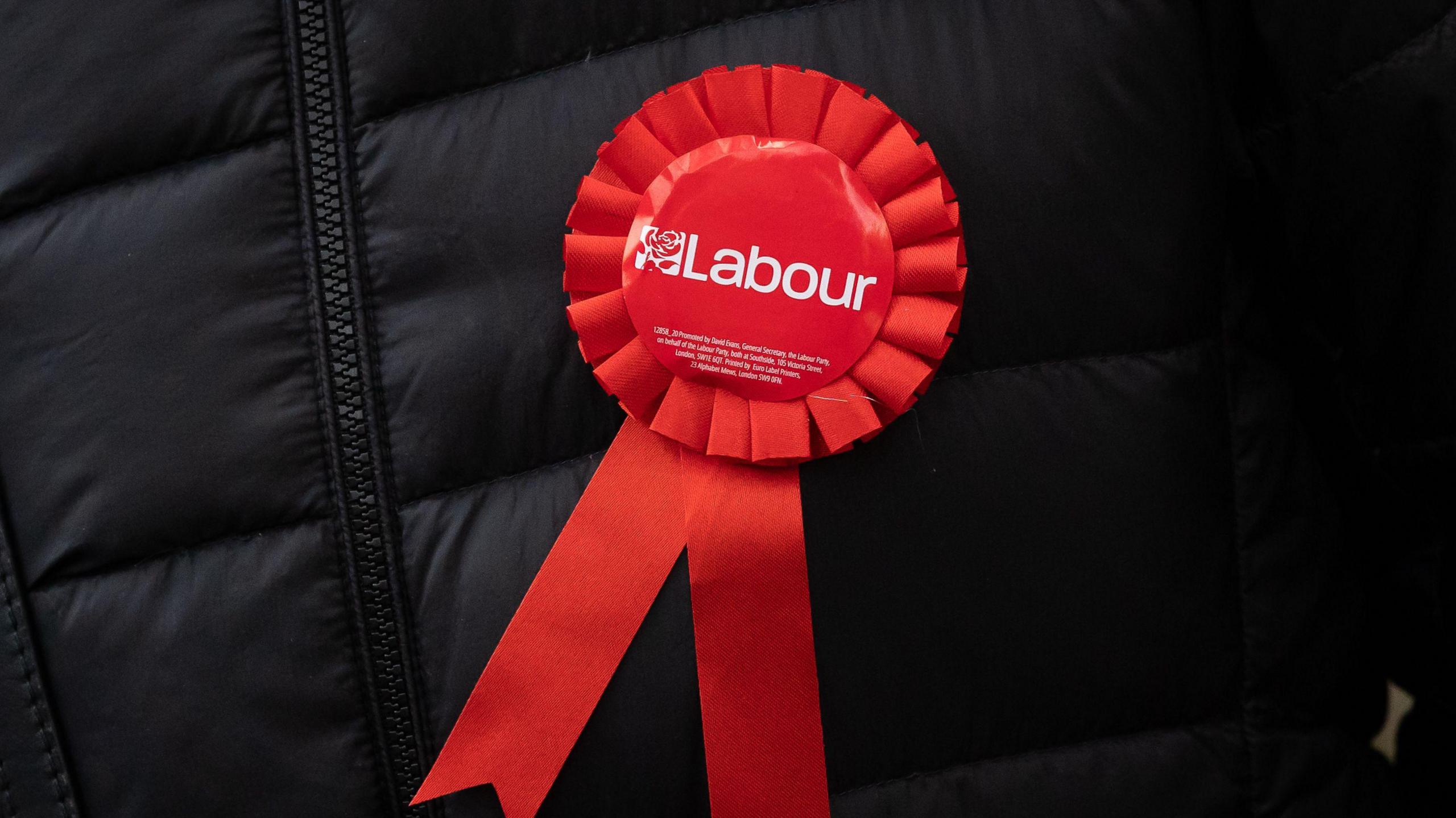 A Labour Party rosette shown on an unidentified man wearing a black coat