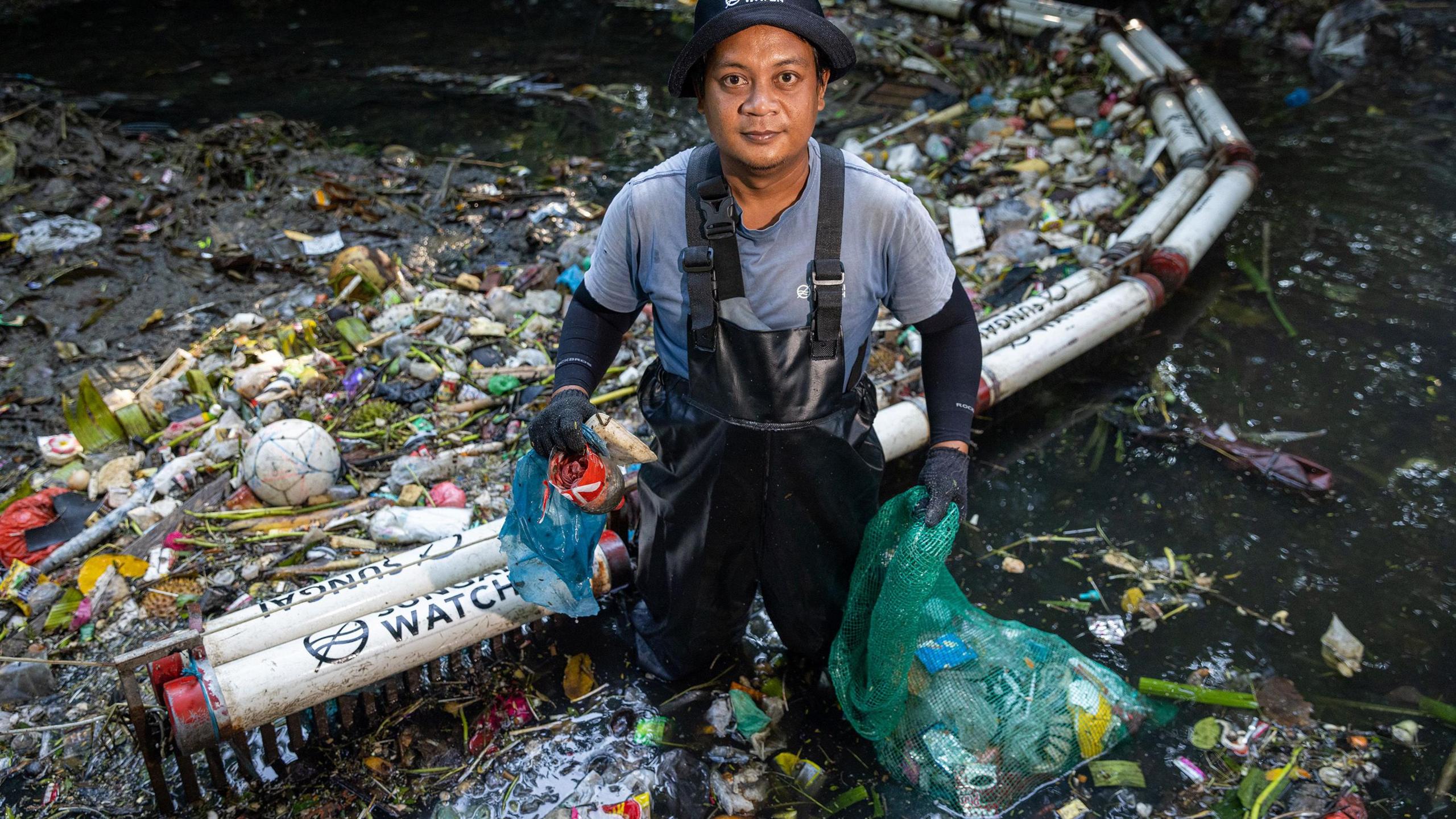 Komang Juniawan stands at a waste barrier in Bali’s mangroves, part of Sungai Watch’s mission to stop plastic pollution, 