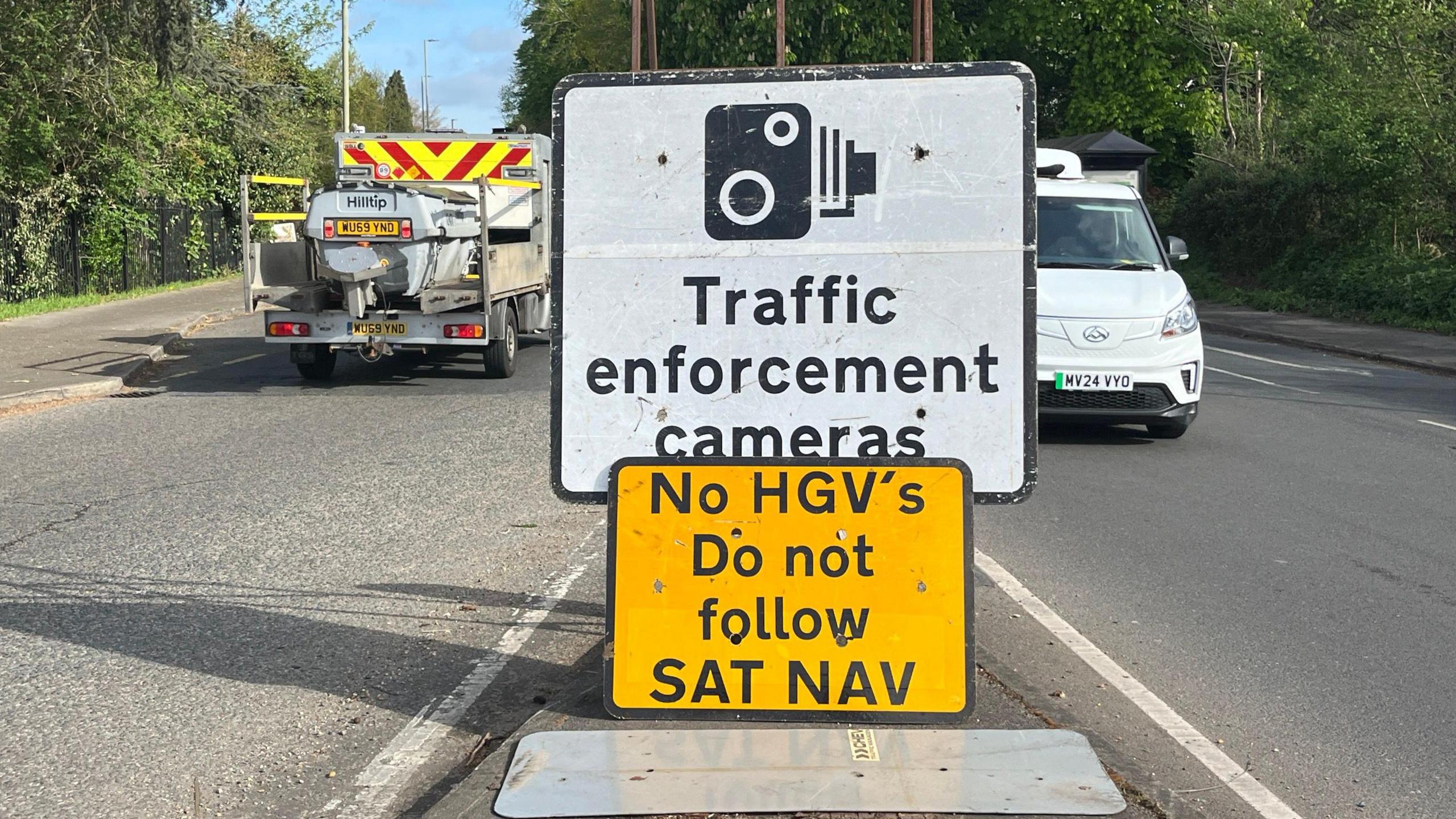 A road sign warning of traffic enforcement cameras, above a second road sign instructing HGV drivers not to follow their sat nav systems.