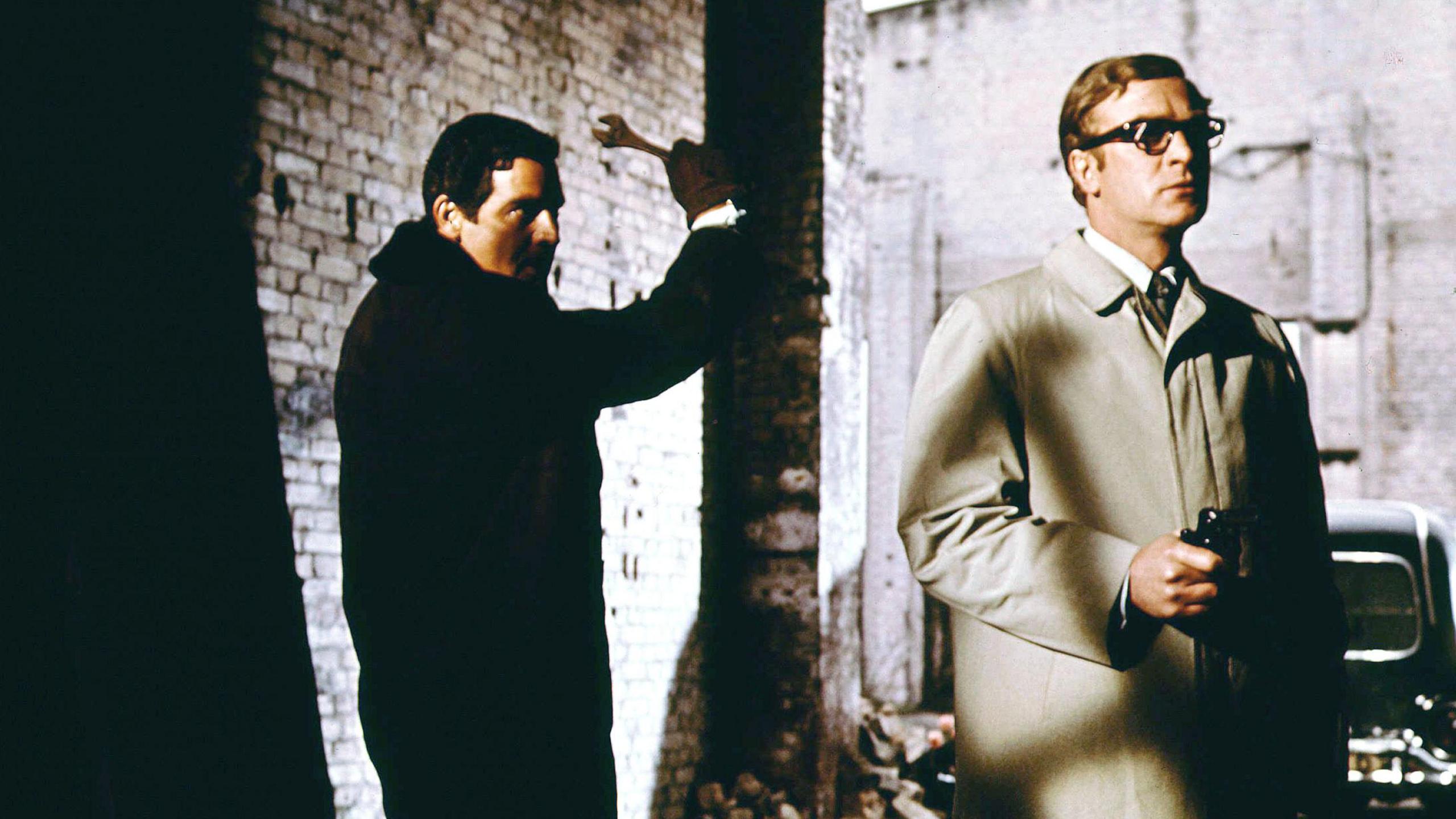 Michael Caine playing Len Deighton's Harry Palmer in Funeral in Berlin. Someone is sneaking up behind Caine with a spanner.  Caine is holding a gun.