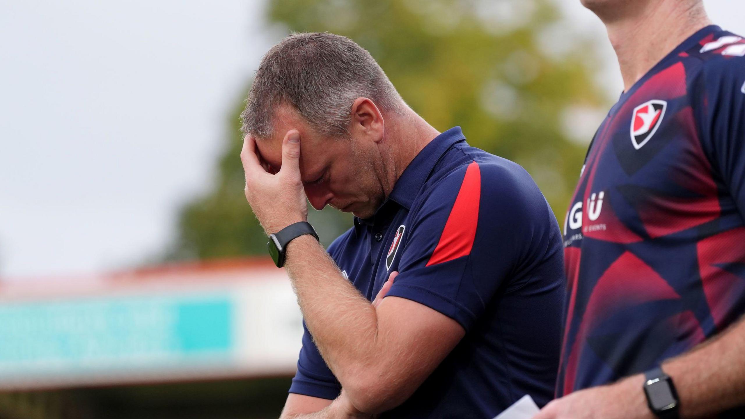 Michael Flynn holds his head in his hands on the touchline