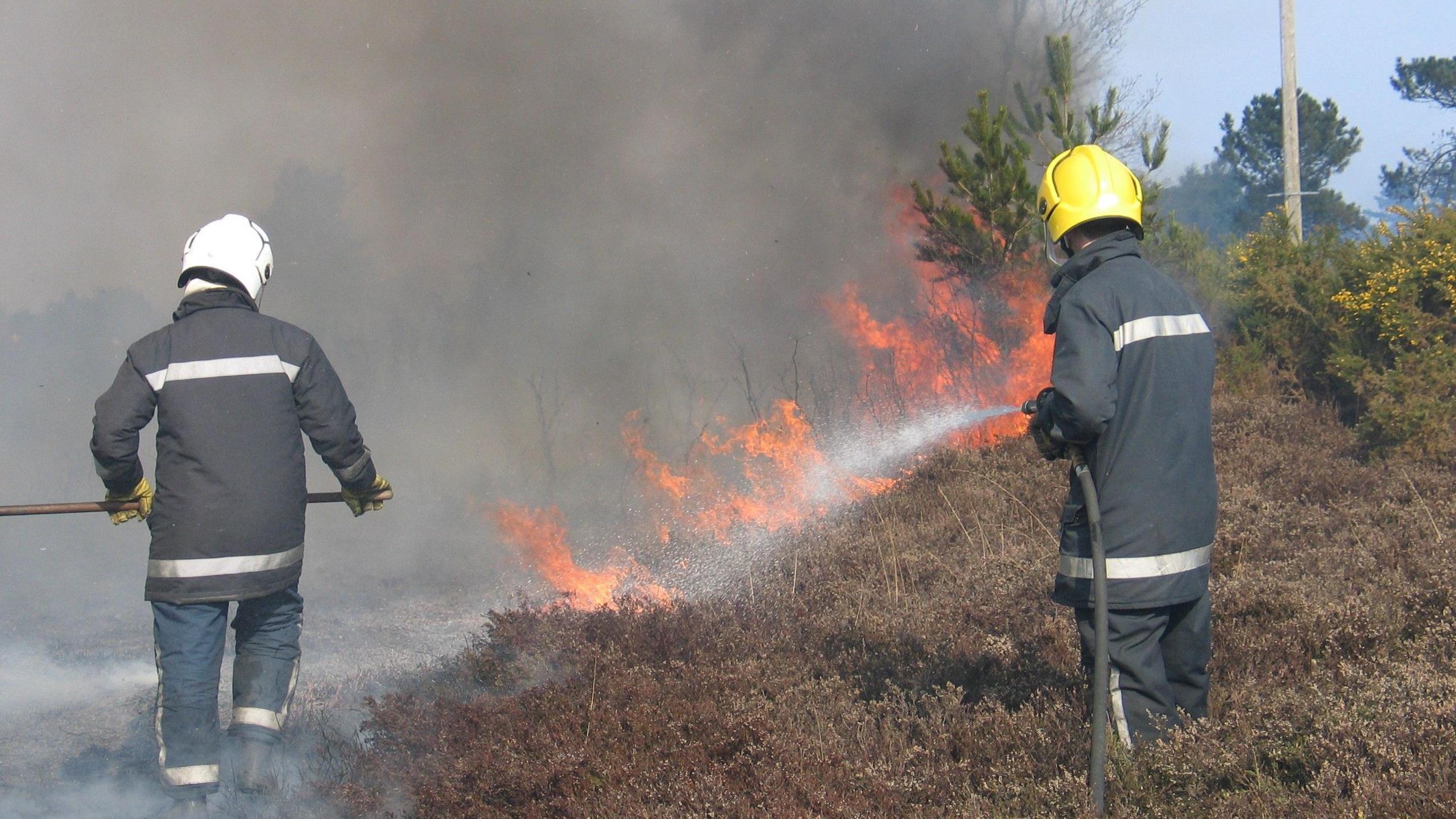 Two retained firefighters tackling a grassland fire
