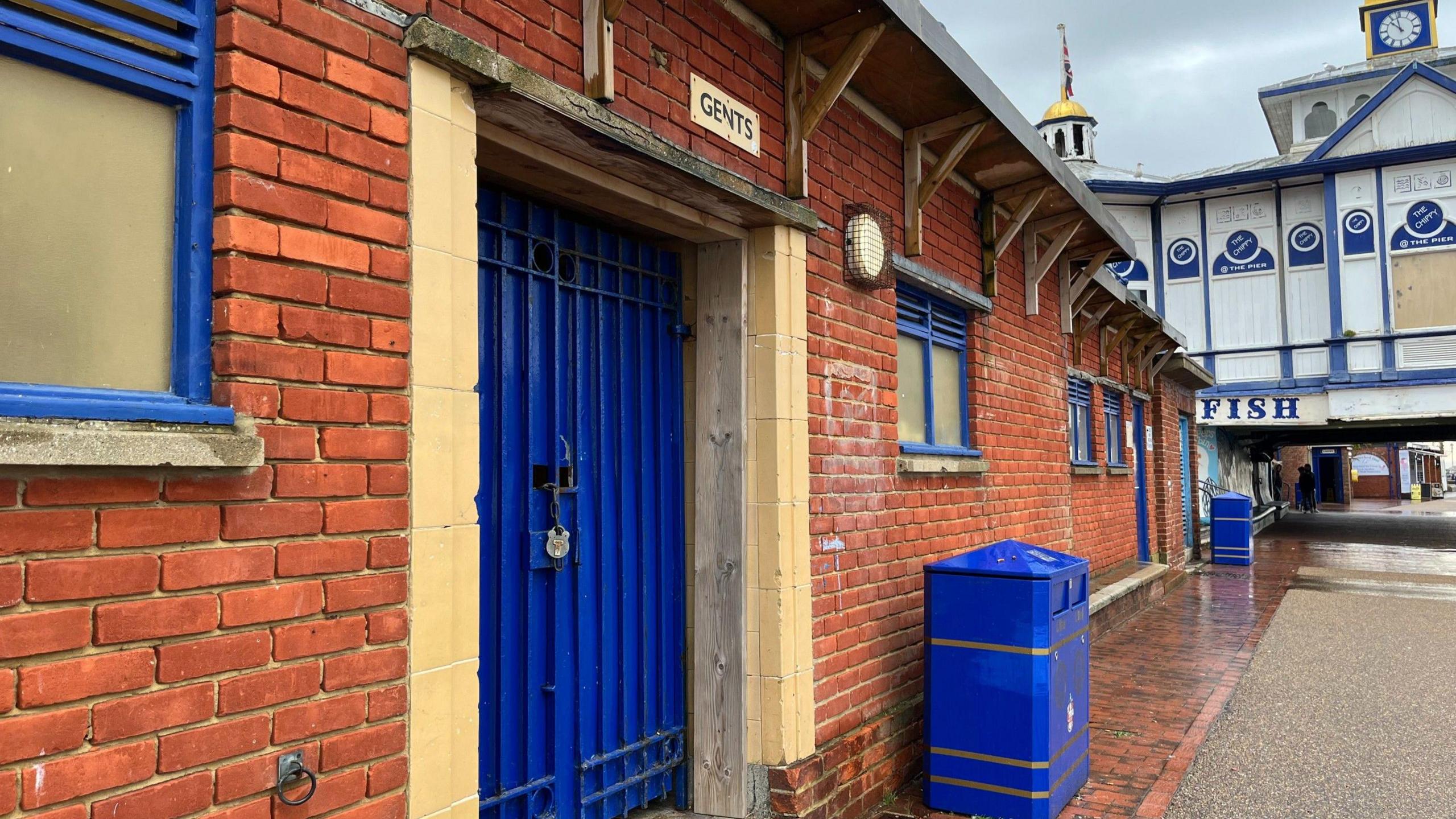 A set of public toilets in Eastbourne, locked up but painted in the district's colours of blue and gold.