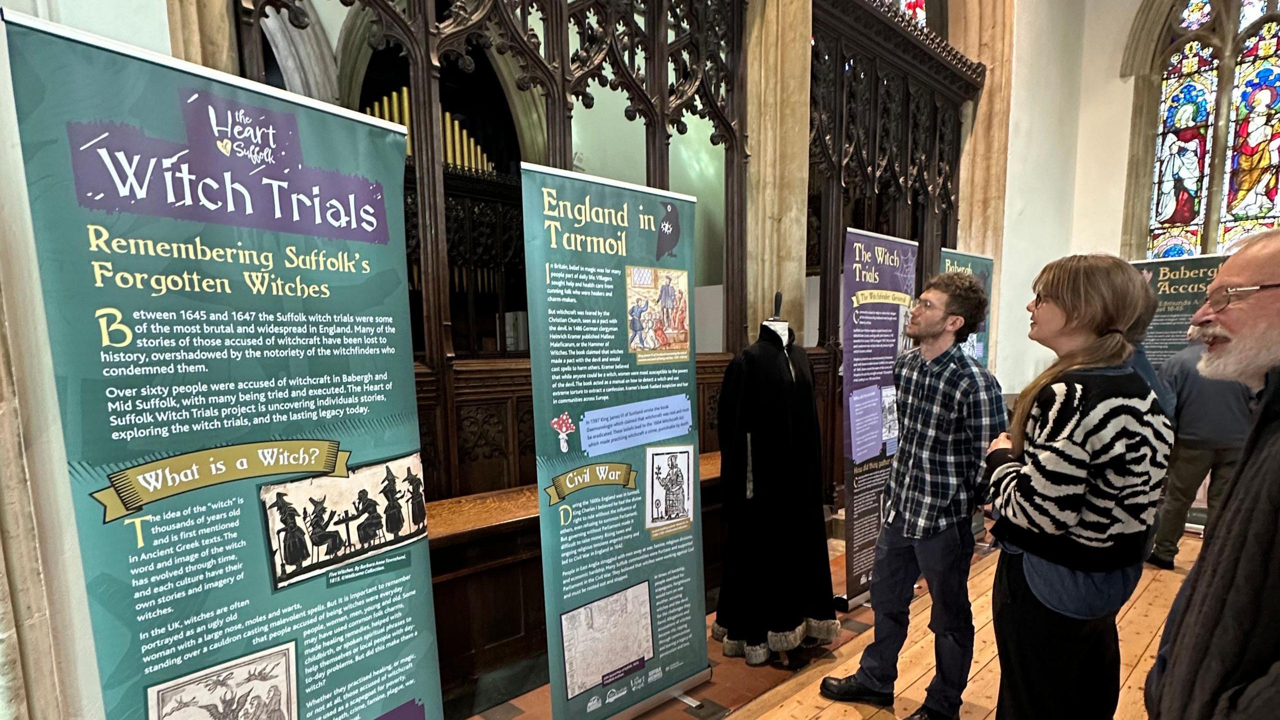 Visitors to the exhibitions standing in front of large boards featuring information about the witch trials