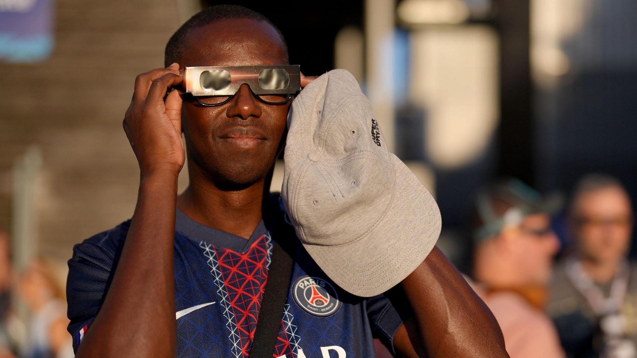 A PSG fan tries to watch the solar eclipse prior to the French side's Super Cup match against Aston Villa 