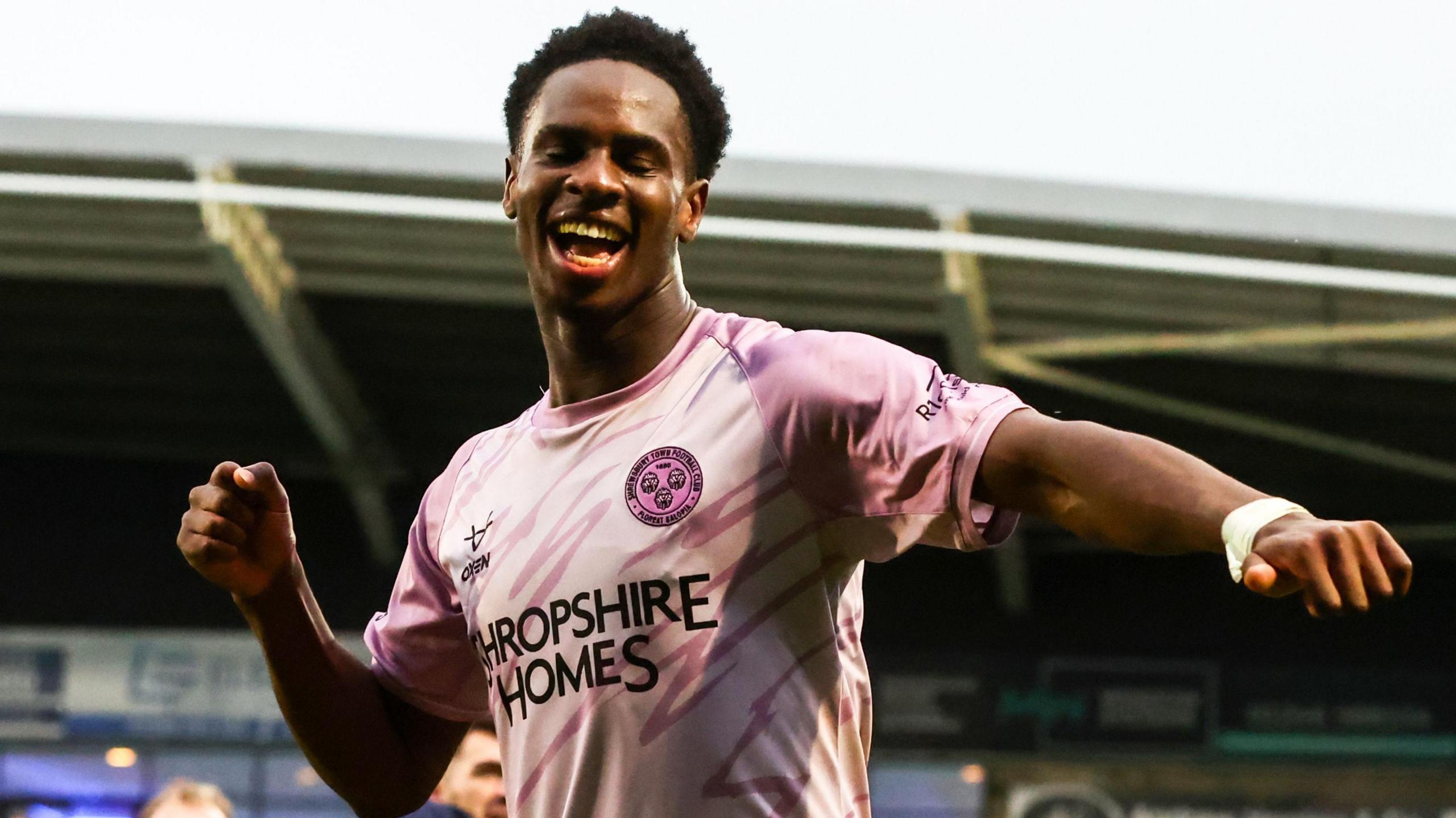 Shrewsbury Town striker Trey Ogunsuyi, wearing the club's pink change strip, celebrates at the final whistle against Chesterfield