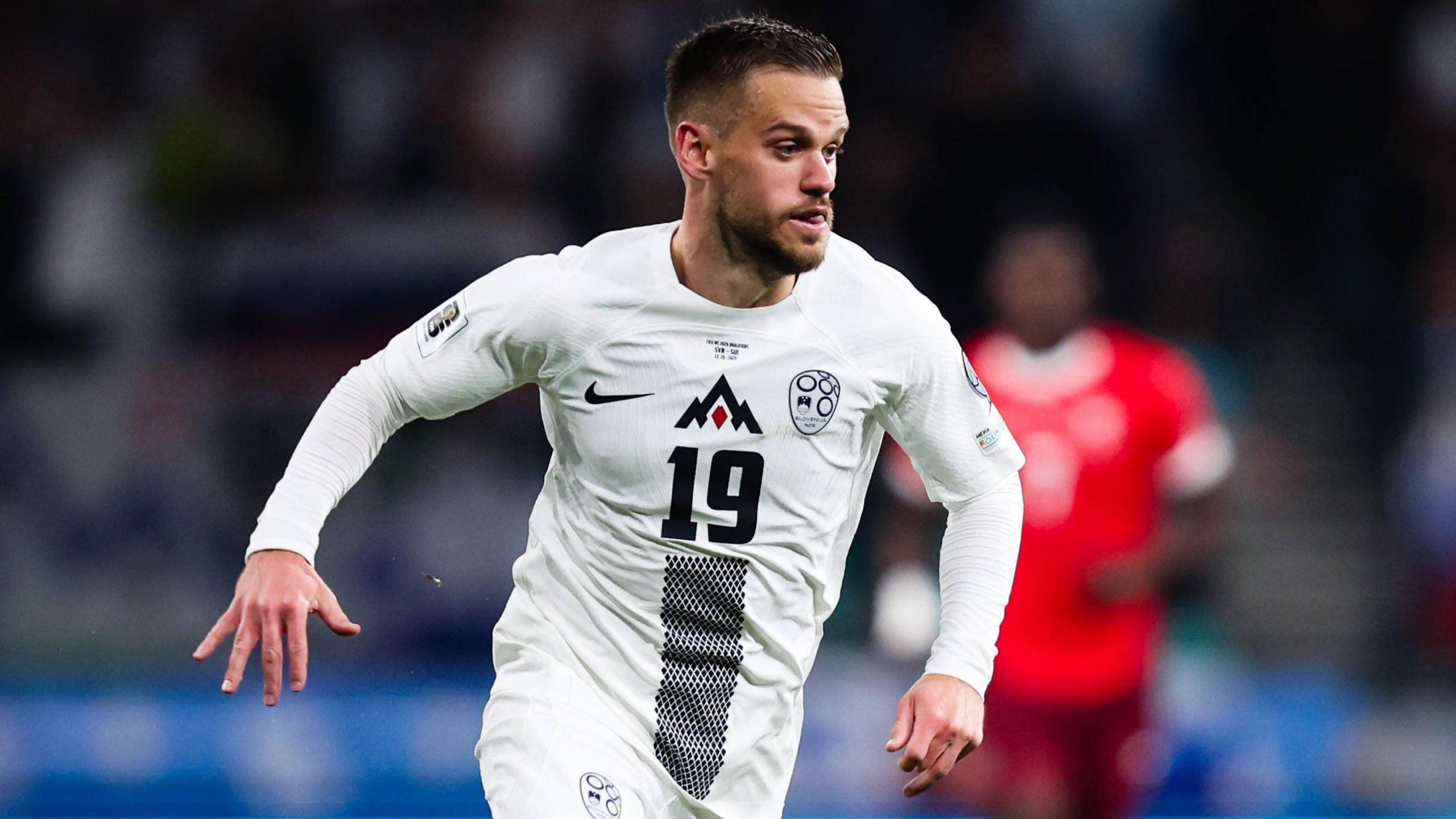 Tomi Horvat running with his arms by his side and the ball at his feet during a World Cup qualifier for Slovenia