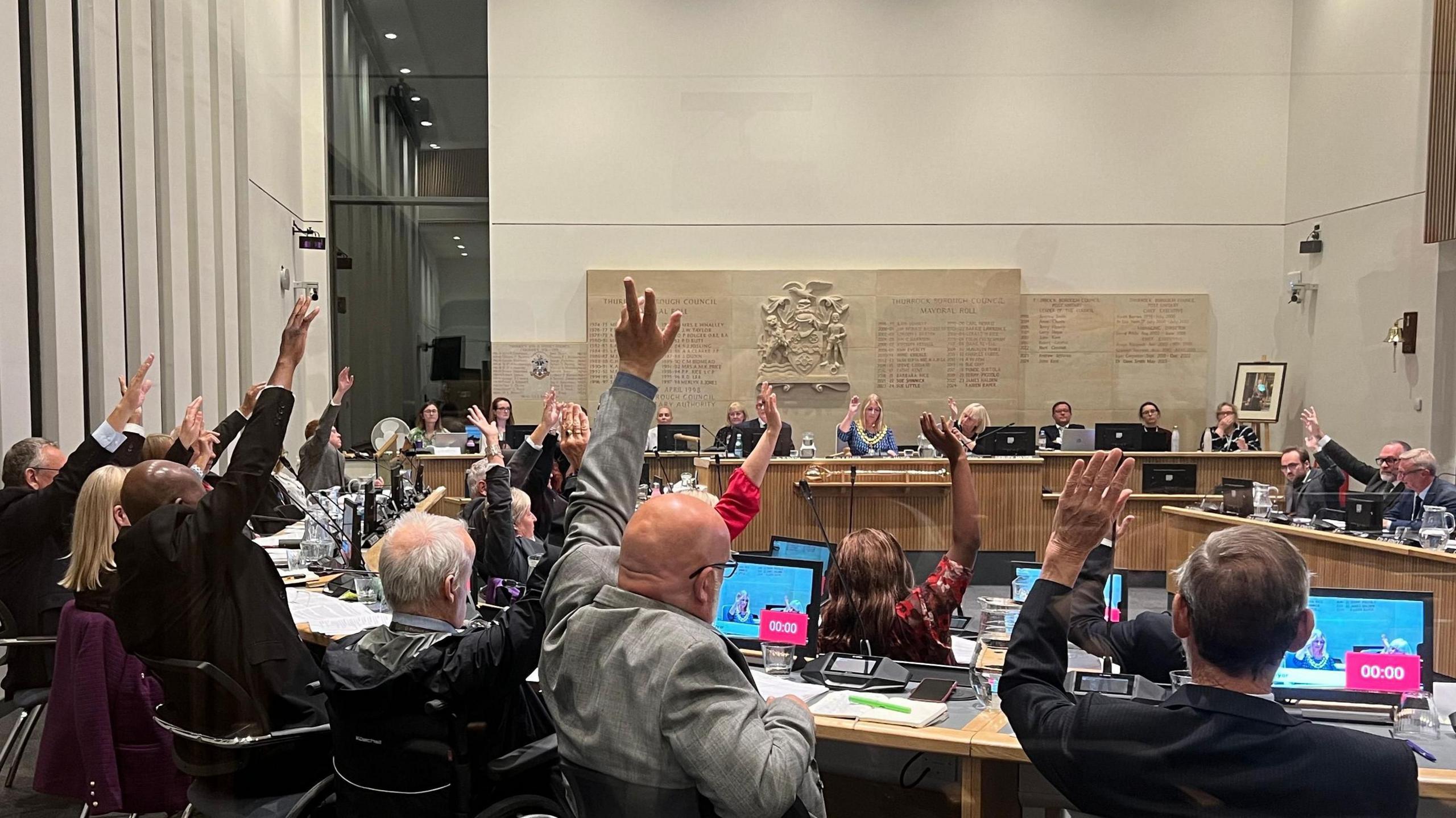 Councillors in the Thurrock Council chamber voting with their hands up